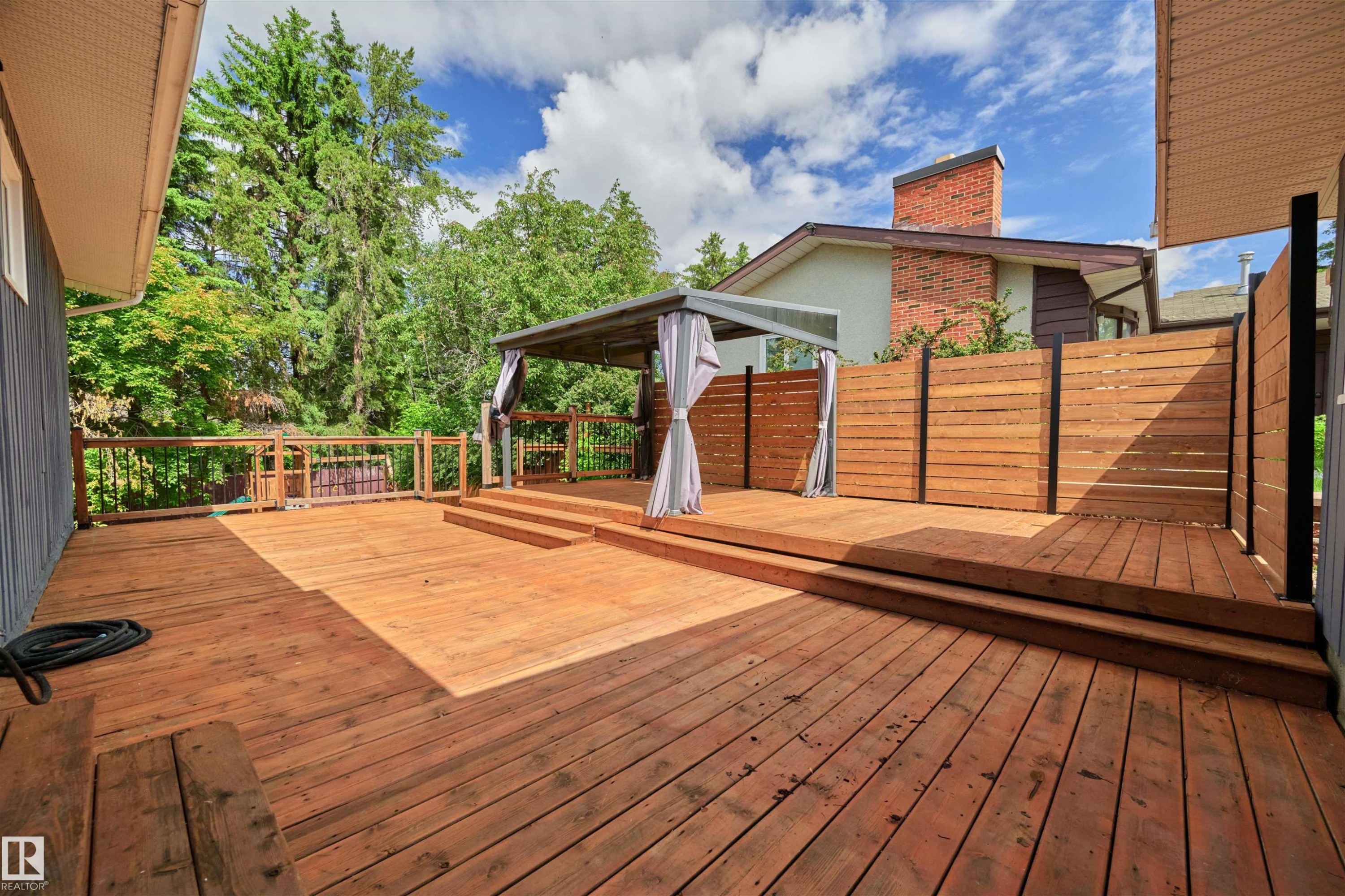 Multi-level wood deck featuring a covered gazebo, integrated privacy screening, and wood railings - 28 Goodridge Drive, St. Albert, AB