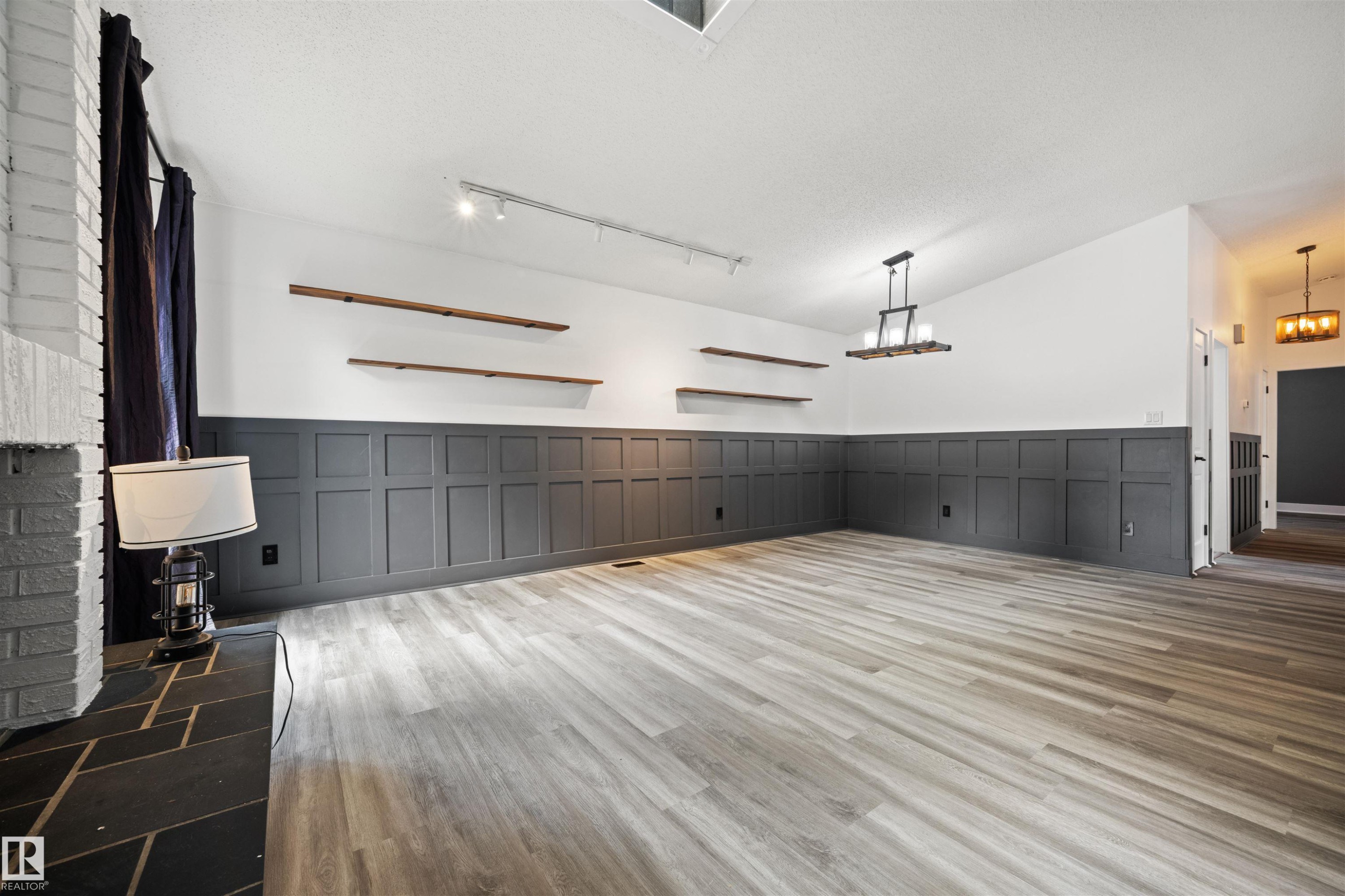 Spacious interior featuring wide plank wood-finish flooring, wainscoting paneling, and a vaulted ceiling - 28 Goodridge Drive, St. Albert, AB