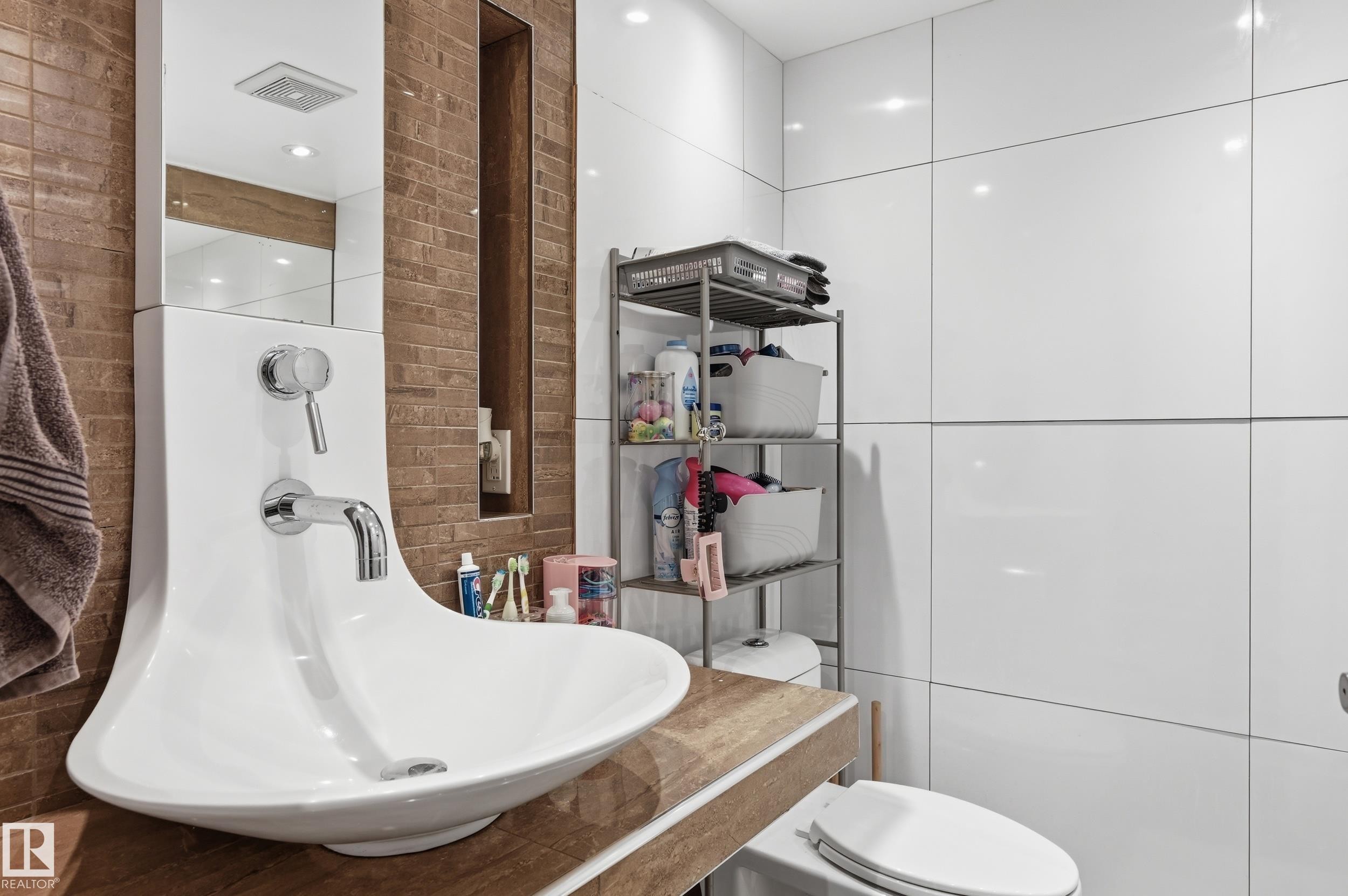 Modern bathroom featuring a unique pedestal sink with integrated chrome faucet, wood-finish countertop, and large format white wall tiles - 12326 92 Street, Edmonton, AB - Indoor Photo Showing Bathroom