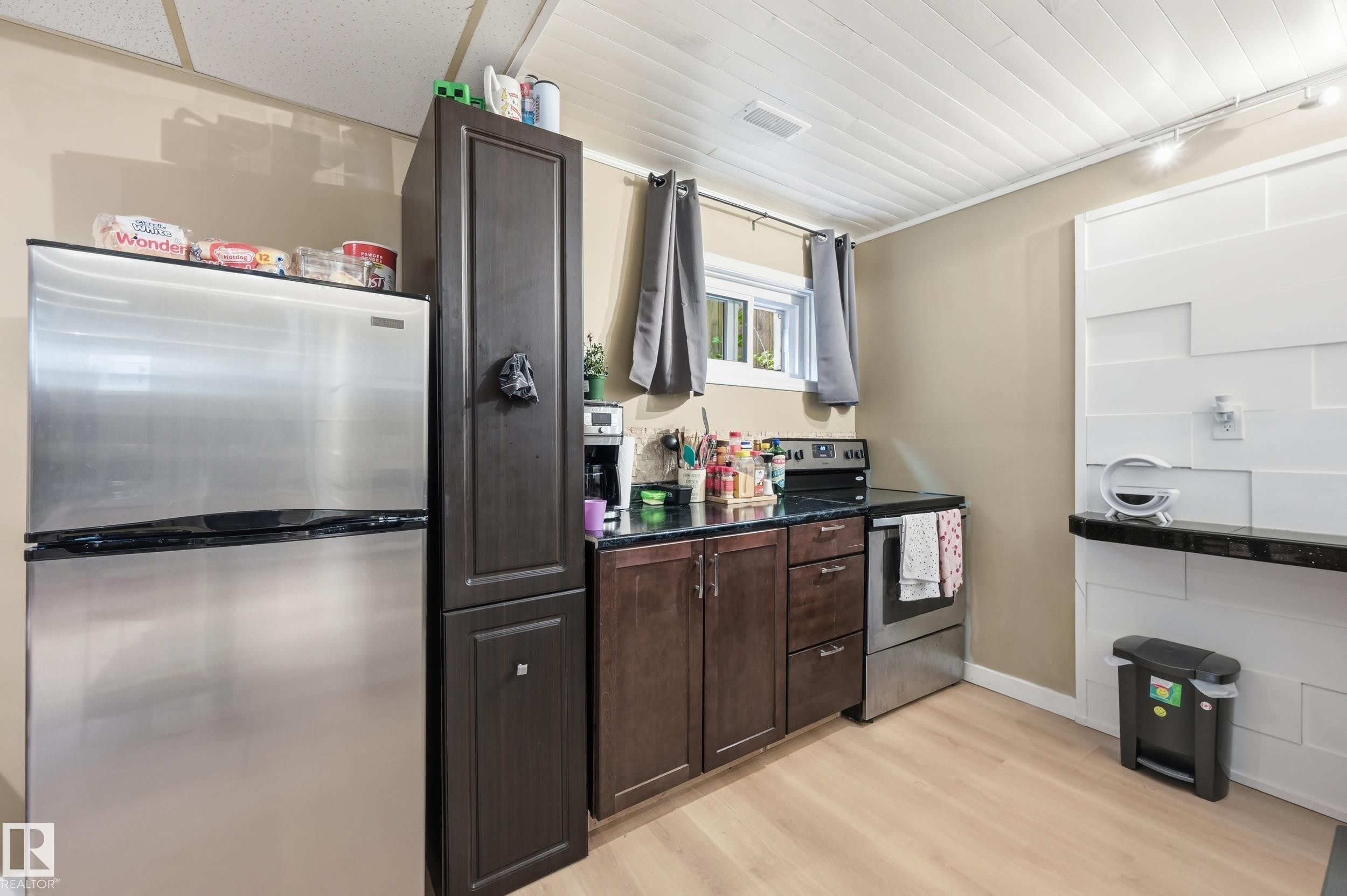 Compact kitchen featuring stainless steel appliances, dark wood cabinetry, and contrasting dark countertops - 12326 92 Street, Edmonton, AB - Indoor Photo Showing Kitchen