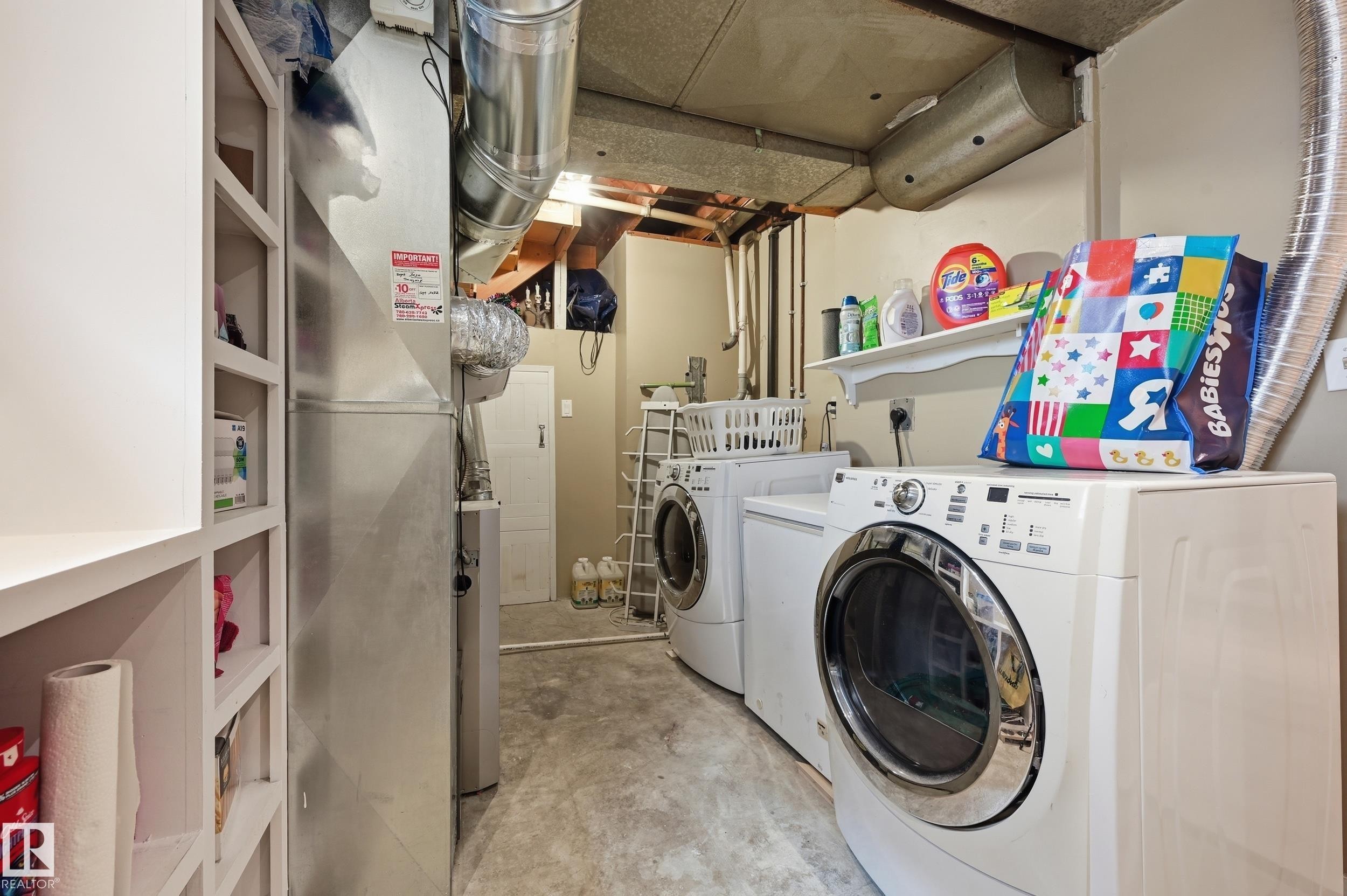 Dedicated utility area featuring a washer and dryer, exposed ductwork, concrete flooring, and built-in shelving - 12326 92 Street, Edmonton, AB - Indoor Photo Showing Laundry Room