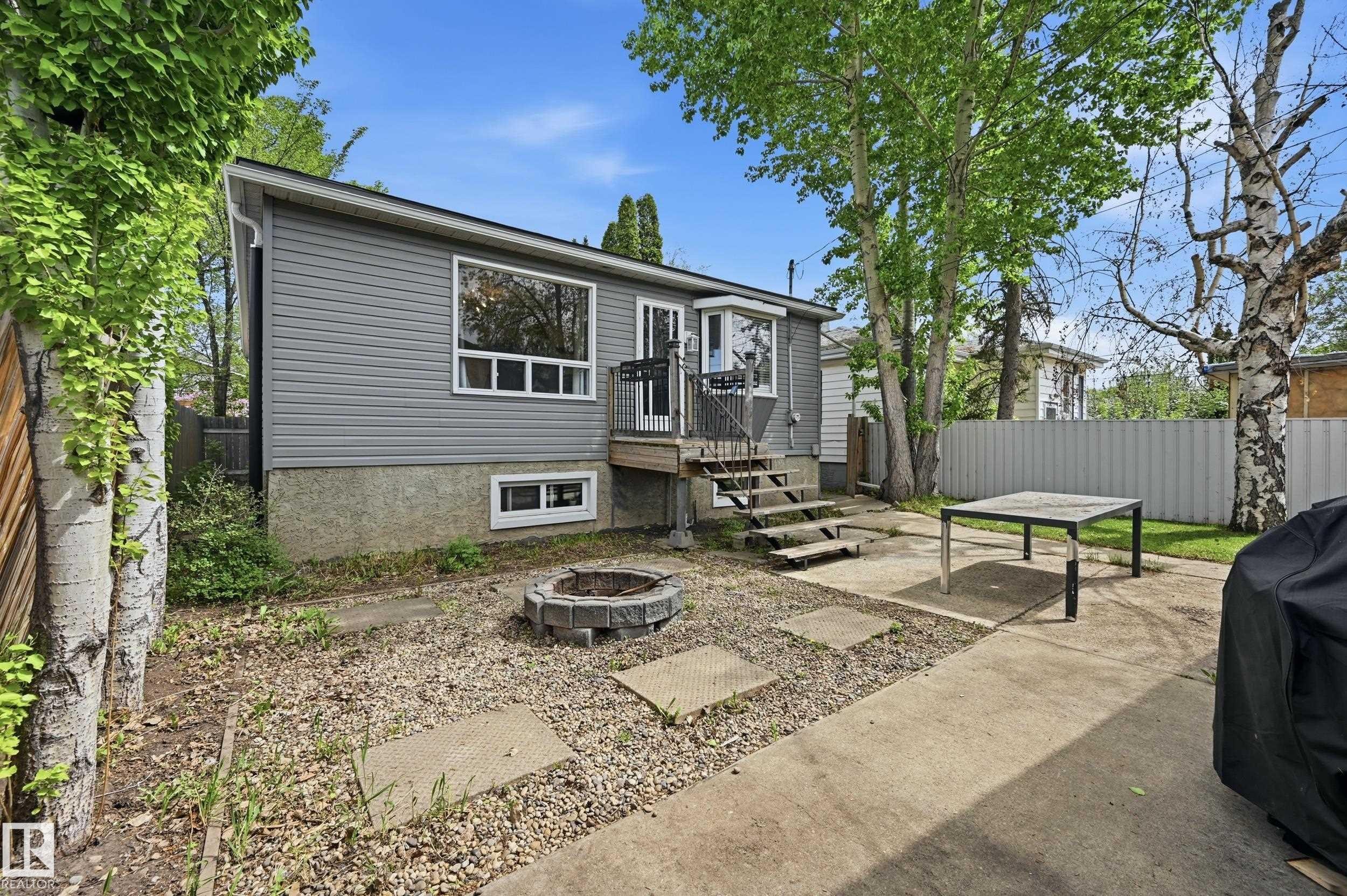 Backyard featuring a concrete patio, stone fire pit, and mature trees - 12326 92 Street, Edmonton, AB - Outdoor