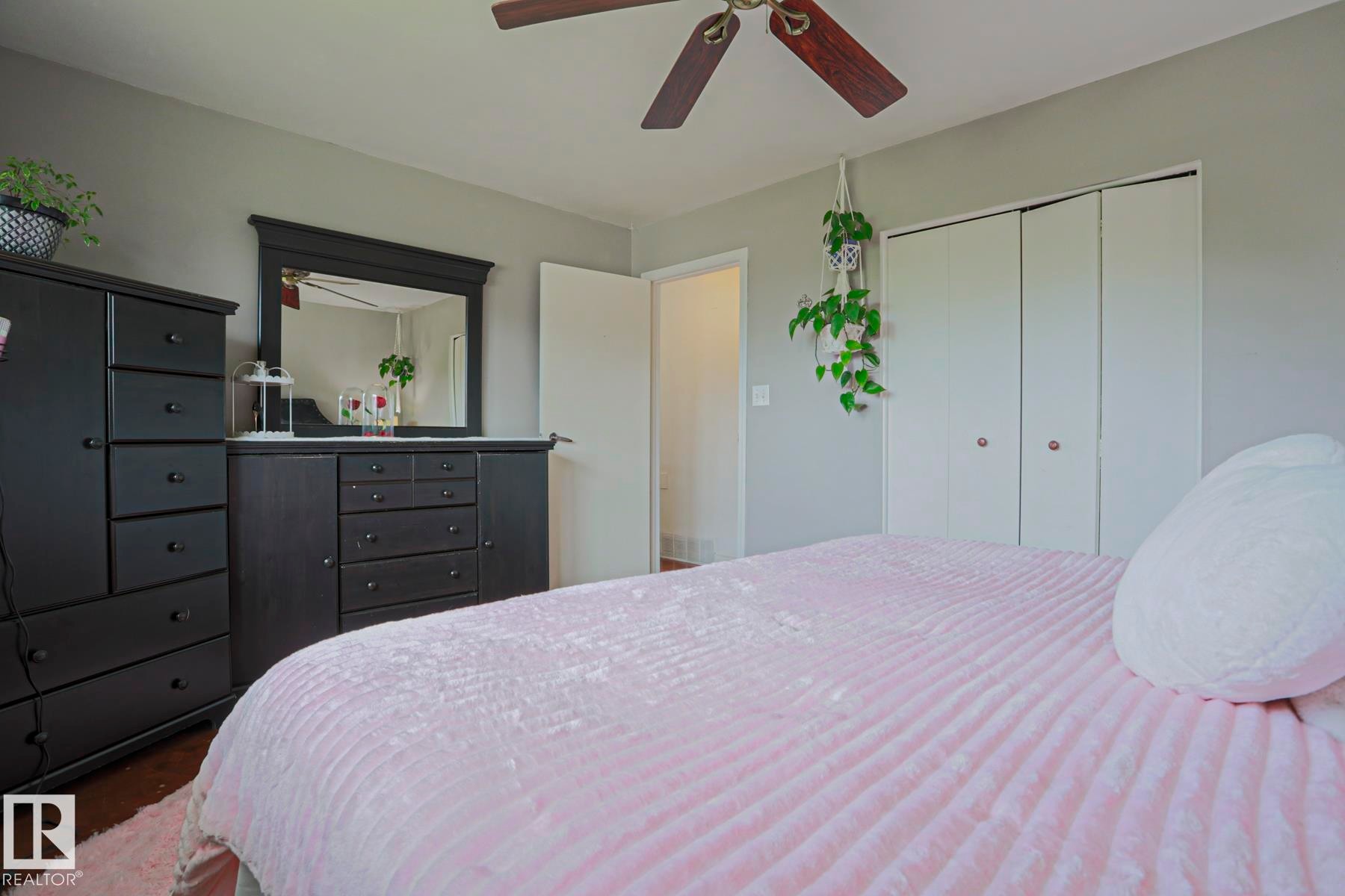 Bedroom featuring wood-finish flooring, light gray walls, and a ceiling fan with wood-tone blades - 2007 67 Street, Edmonton, AB