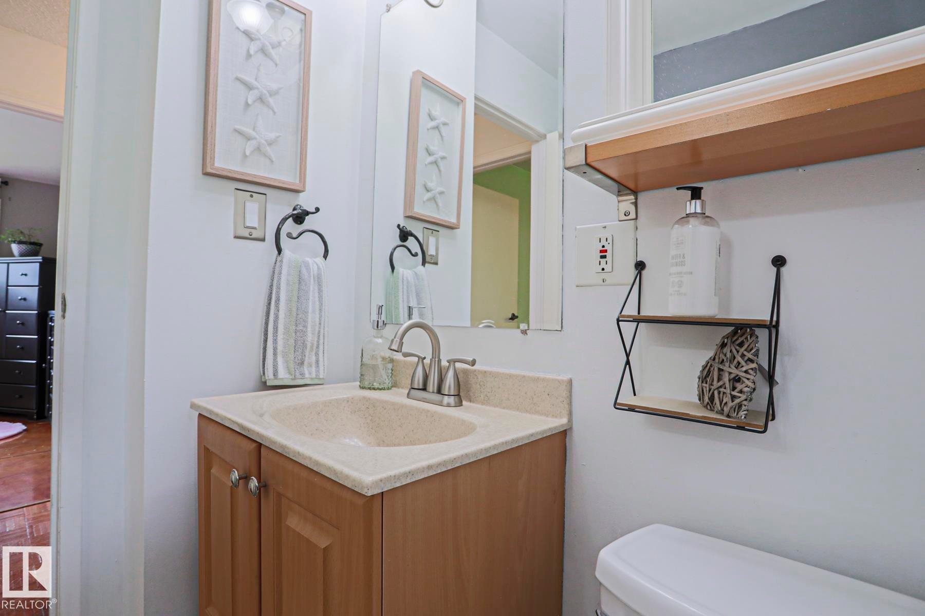 Bathroom vanity with an integrated sink, brushed nickel faucet, and wood-finish cabinetry - 2007 67 Street, Edmonton, AB
