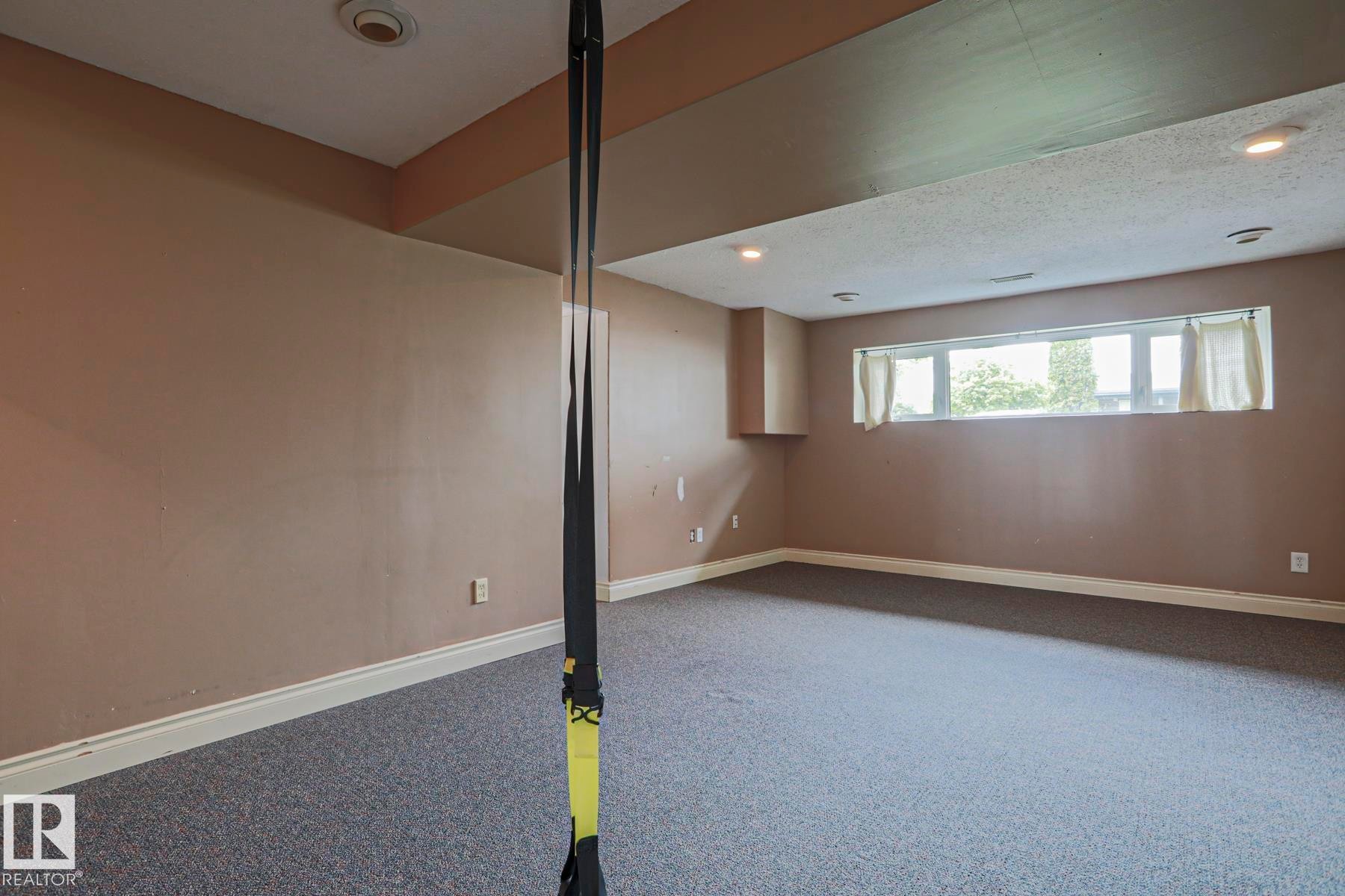 Spacious room featuring neutral-toned walls, recessed lighting, and a large horizontal window - 2007 67 Street, Edmonton, AB