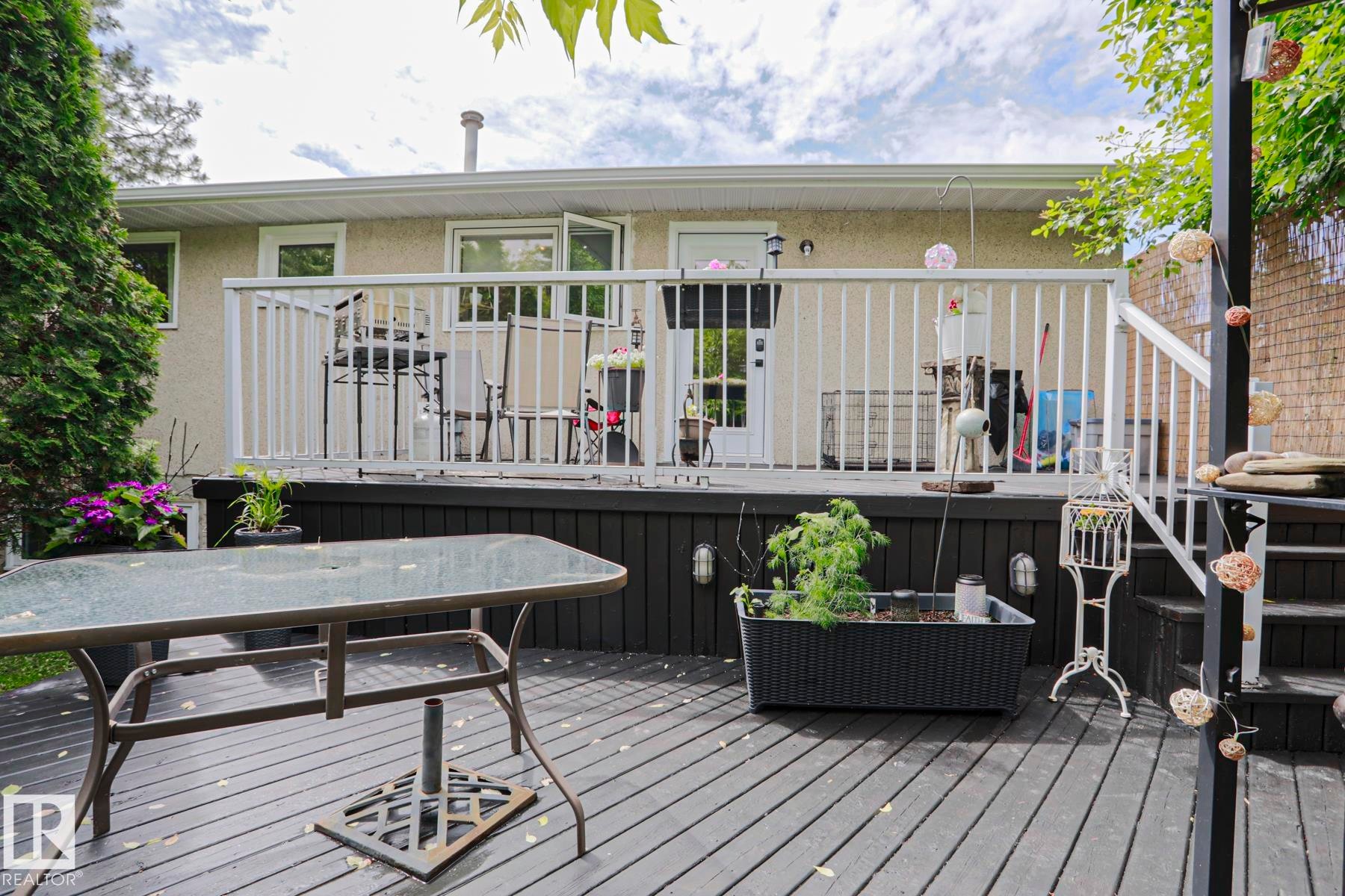 Spacious multi-level deck featuring dark wood-finish flooring, white railings, and a walk-out from the home's exterior - 2007 67 Street, Edmonton, AB