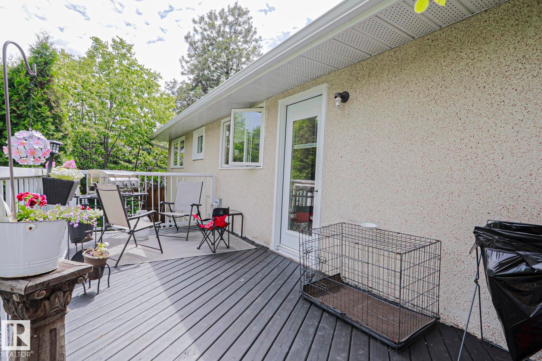 Expansive rear deck featuring dark wood-finish planking, white railing, and a textured exterior wall - 2007 67 Street, Edmonton, AB
