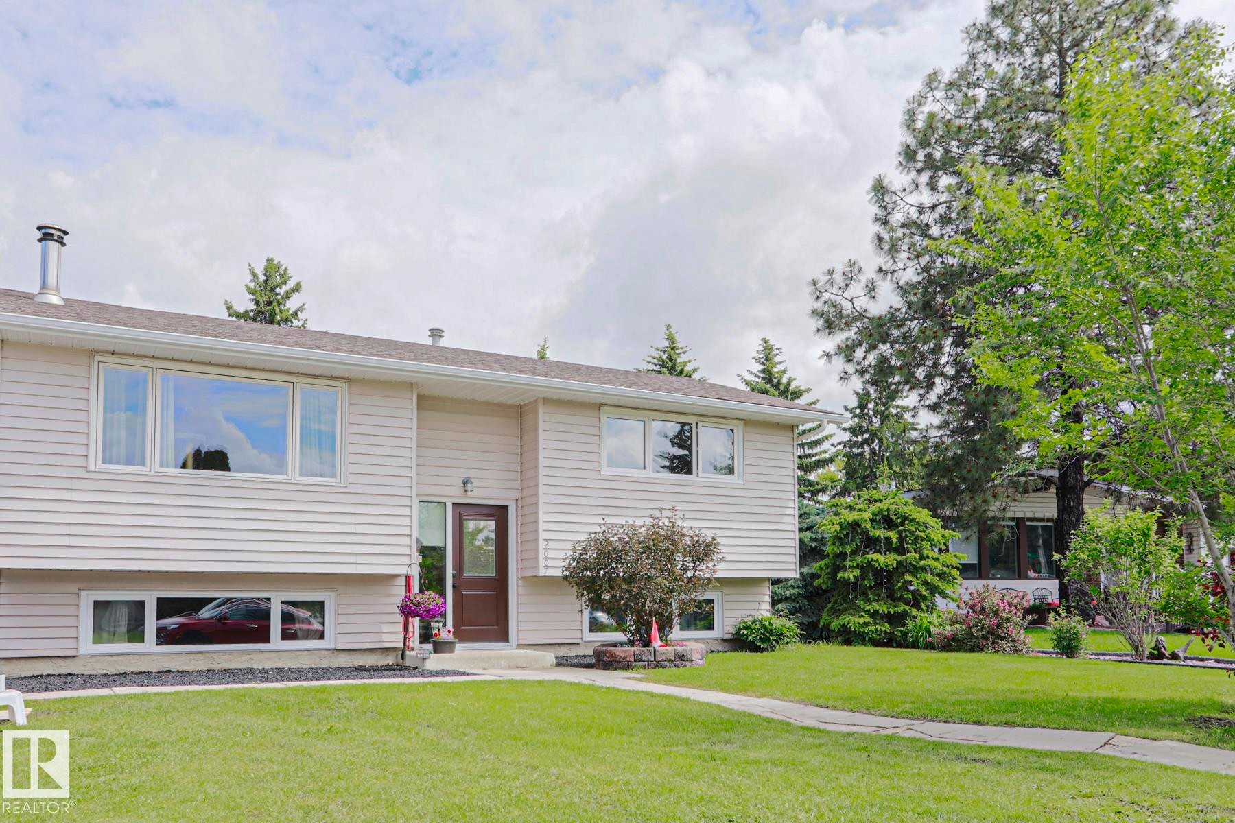 Split-level residence featuring light-colored siding, a dark brown entry door with transom window, and white window frames - 2007 67 Street, Edmonton, AB