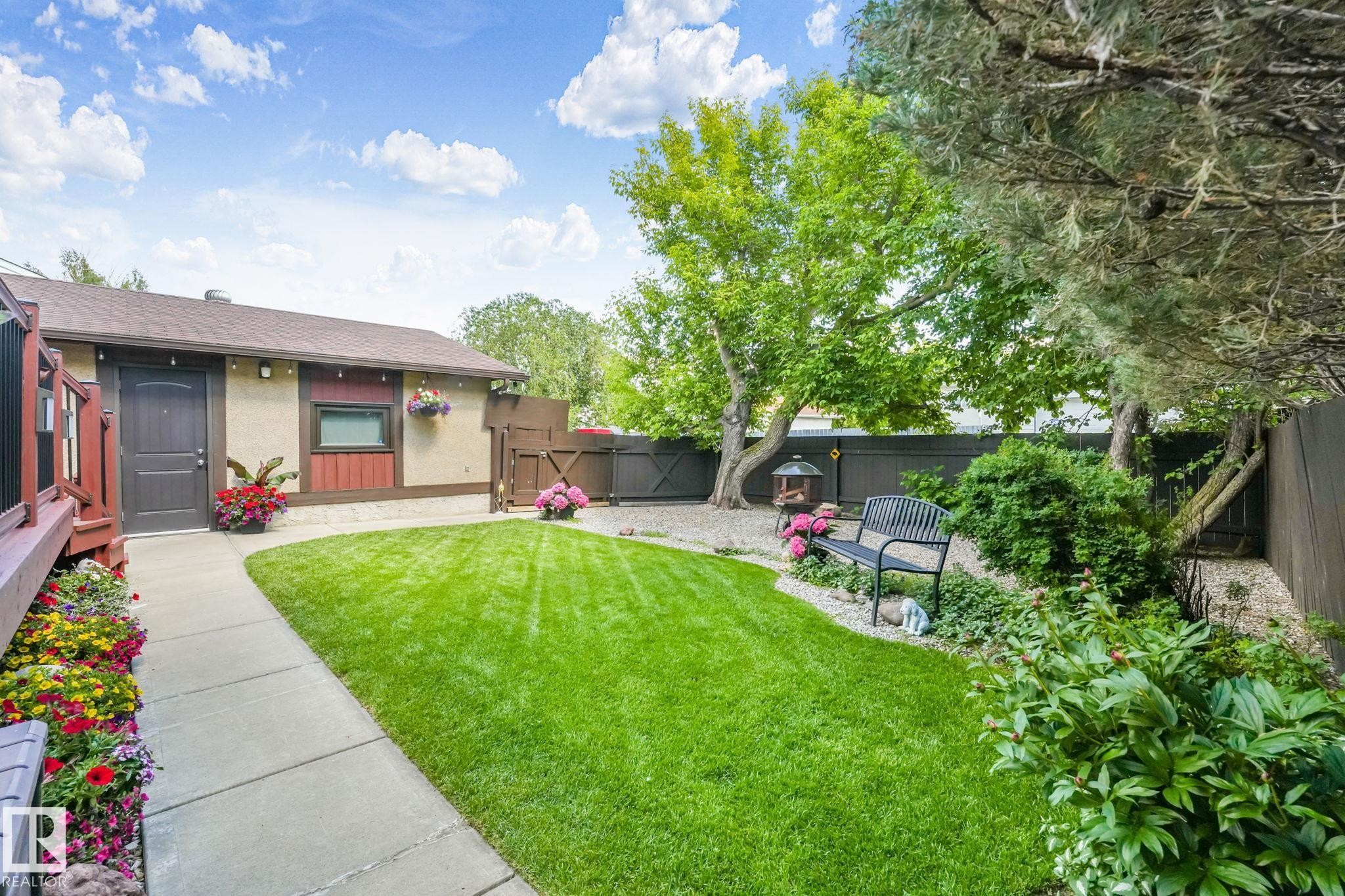 Manicured lawn with a concrete pathway leading to a building with stucco and wood siding - 17237 104 Street, Edmonton, AB