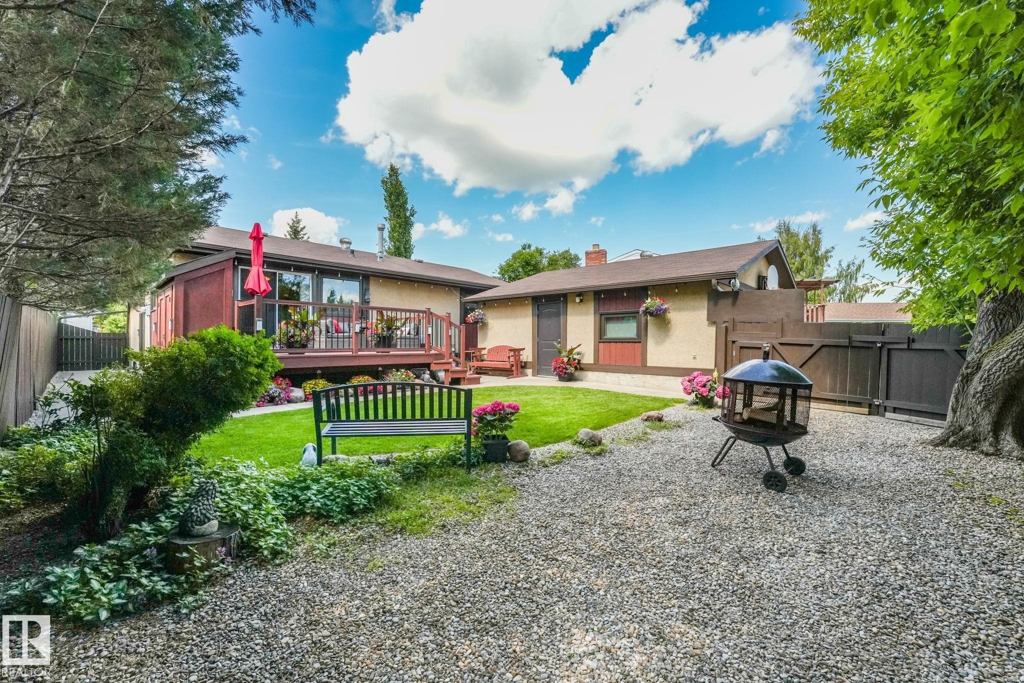 Expansive backyard featuring a gravel patio, manicured lawn, and mature perimeter trees - 17237 104 Street, Edmonton, AB