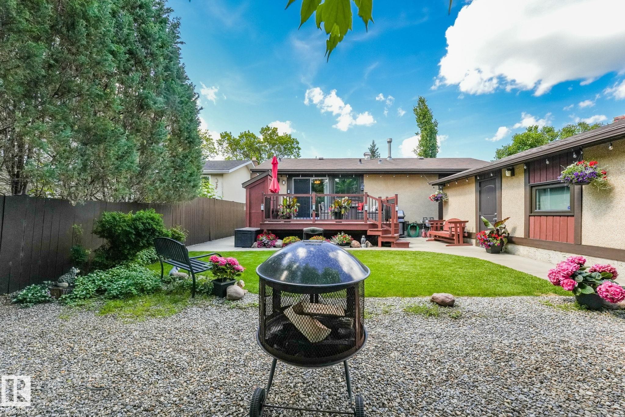 Expansive backyard featuring a gravel patio, manicured lawn, and a wooden deck - 17237 104 Street, Edmonton, AB
