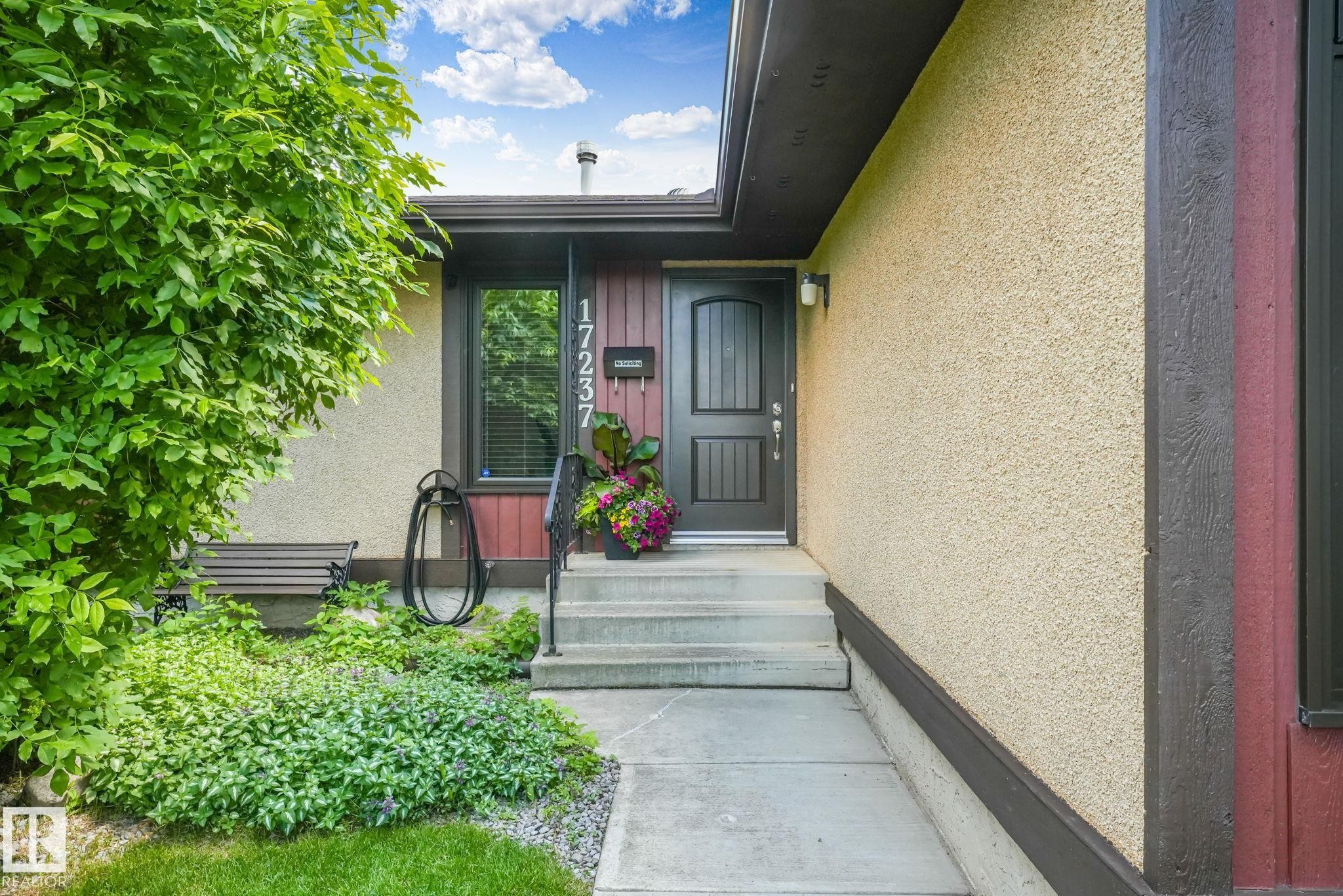 Stucco exterior with dark trim accents and a dark paneled entry door - 17237 104 Street, Edmonton, AB