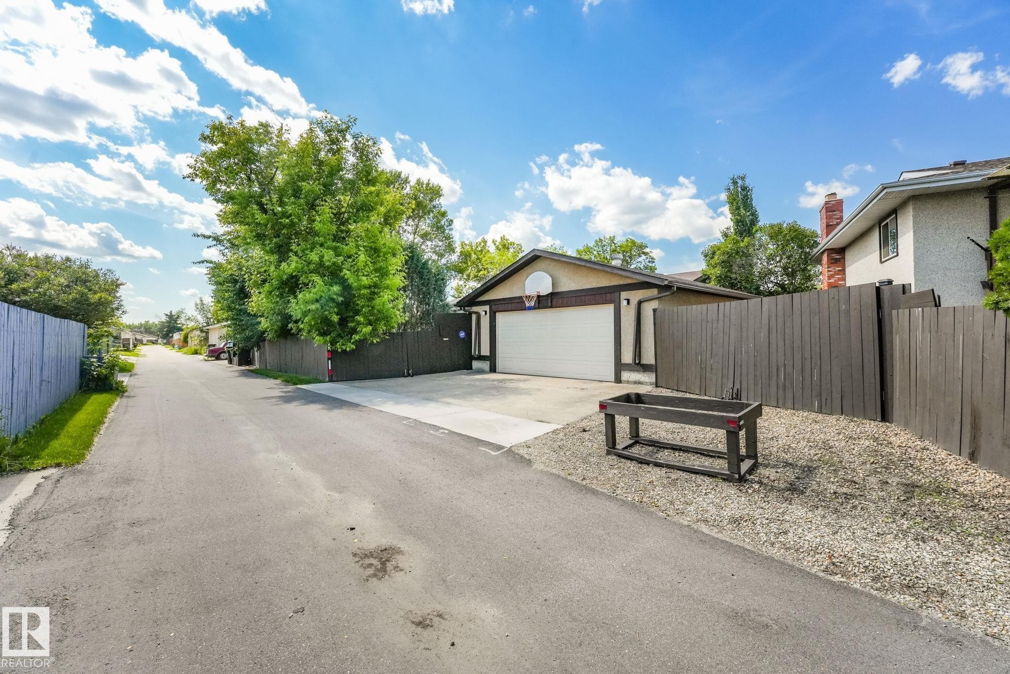Detached garage with a white overhead door, adjacent to a gravel landscaped area and wood fencing - 17237 104 Street, Edmonton, AB