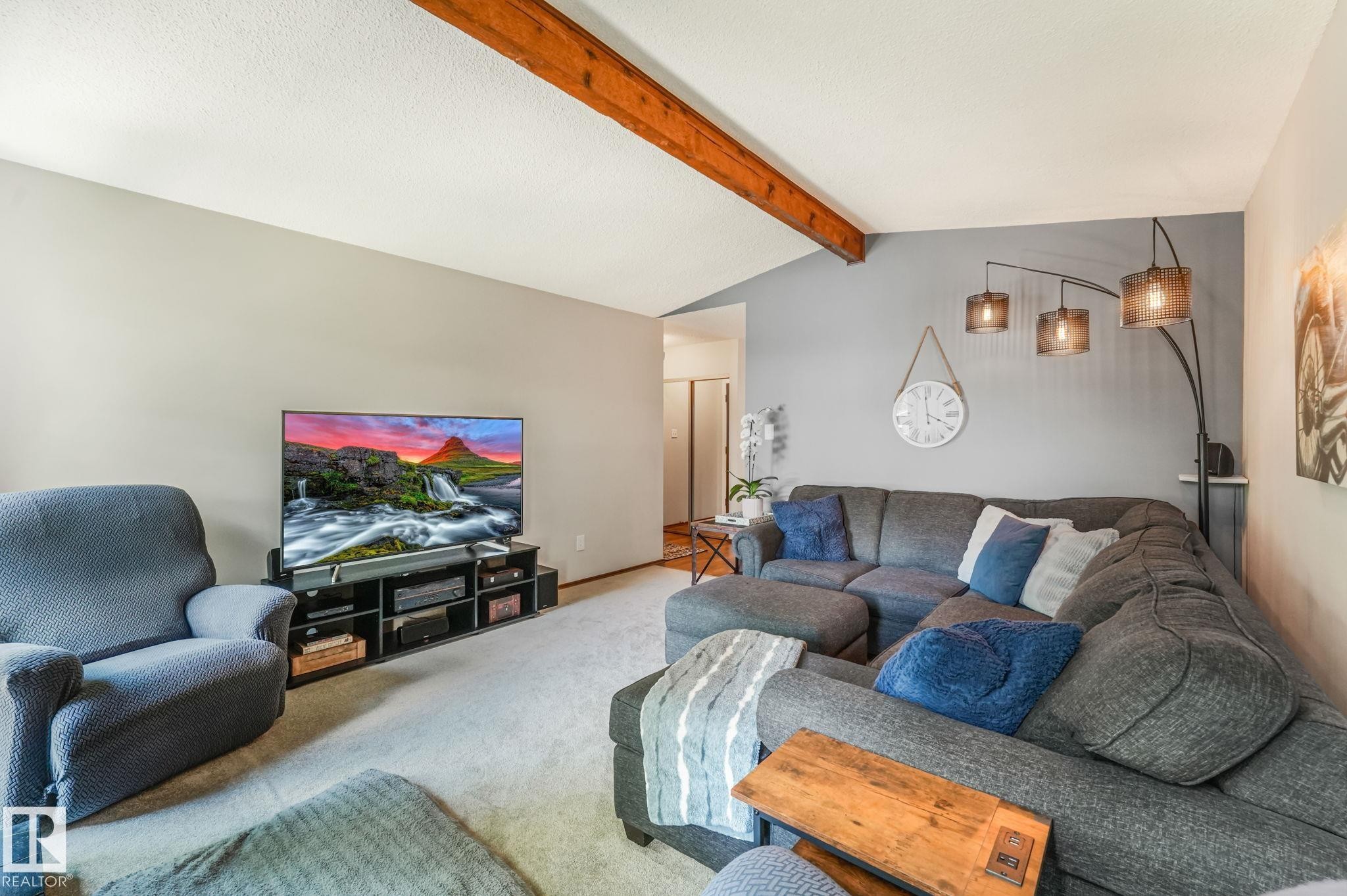 Vaulted ceiling with exposed wood beam and textured finish, light gray wall paint, and plush carpet flooring - 17237 104 Street, Edmonton, AB