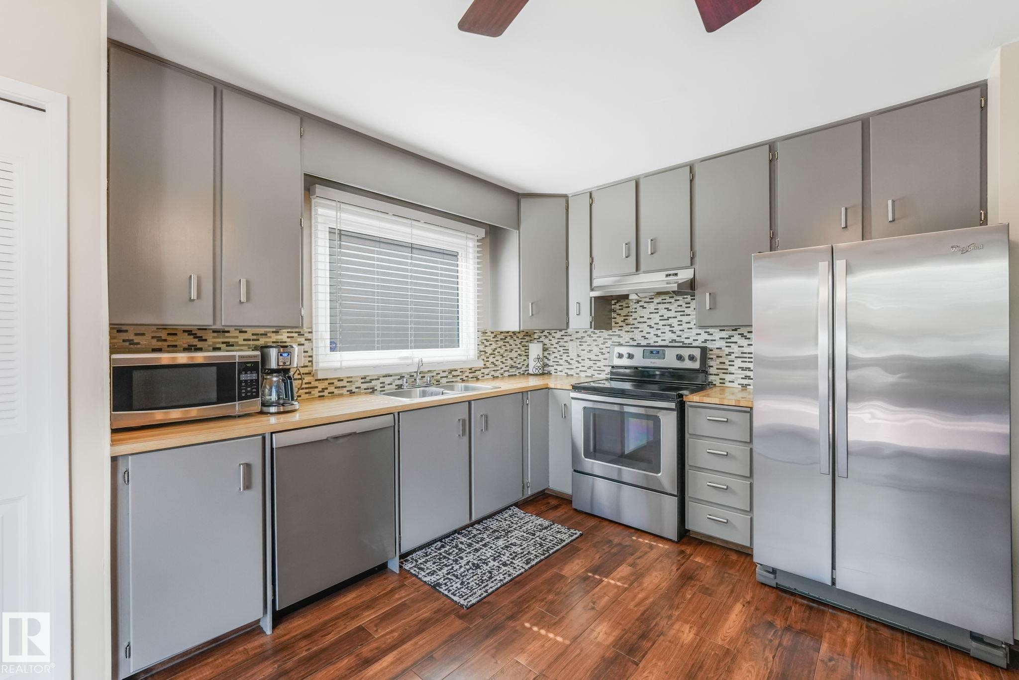 Kitchen featuring wood-finish flooring, gray cabinetry, and light wood-tone countertops - 17237 104 Street, Edmonton, AB