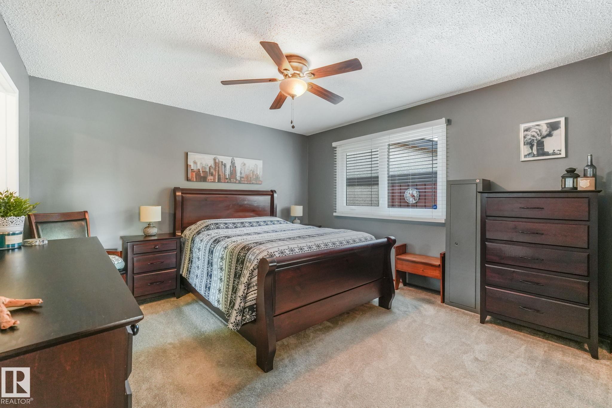 Carpeted bedroom with a window featuring white blinds, gray wall paint, and a ceiling fan with integrated lighting - 17237 104 Street, Edmonton, AB