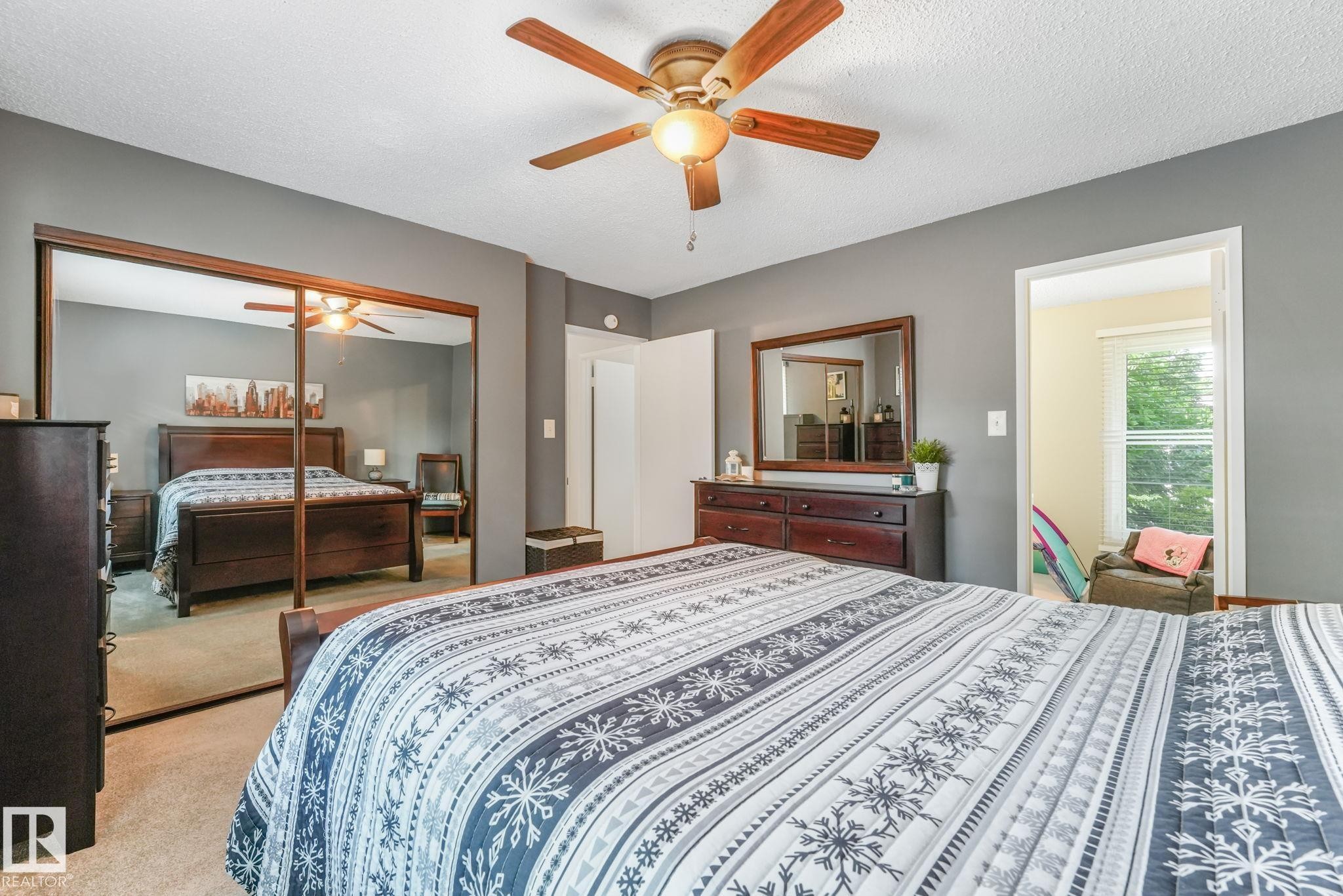 Bedroom featuring neutral gray walls, a ceiling fan with light fixture, carpeted flooring, and mirrored closet doors - 17237 104 Street, Edmonton, AB