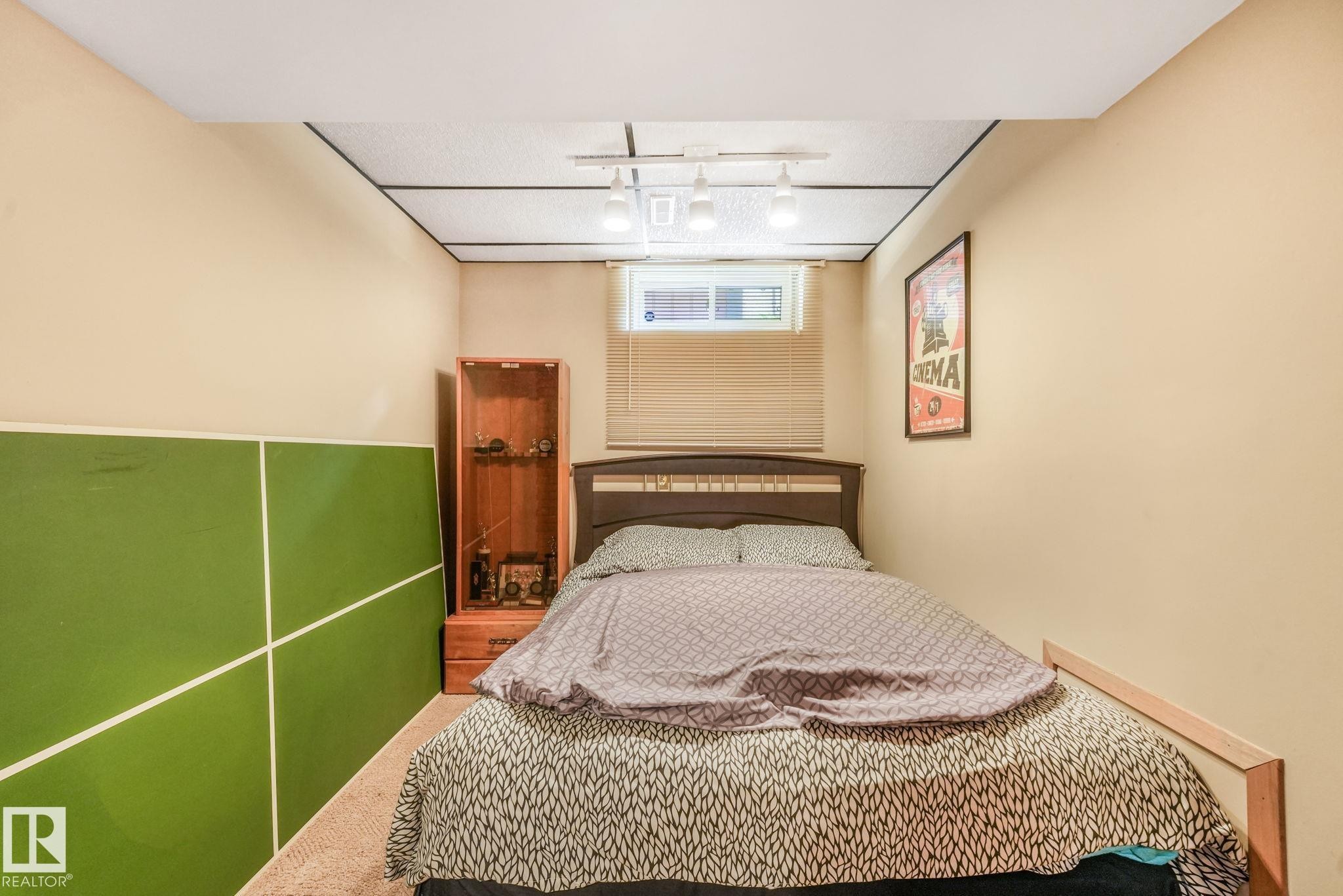 Neutral-toned room featuring a wood-finish bed frame with a slatted headboard - 17237 104 Street, Edmonton, AB