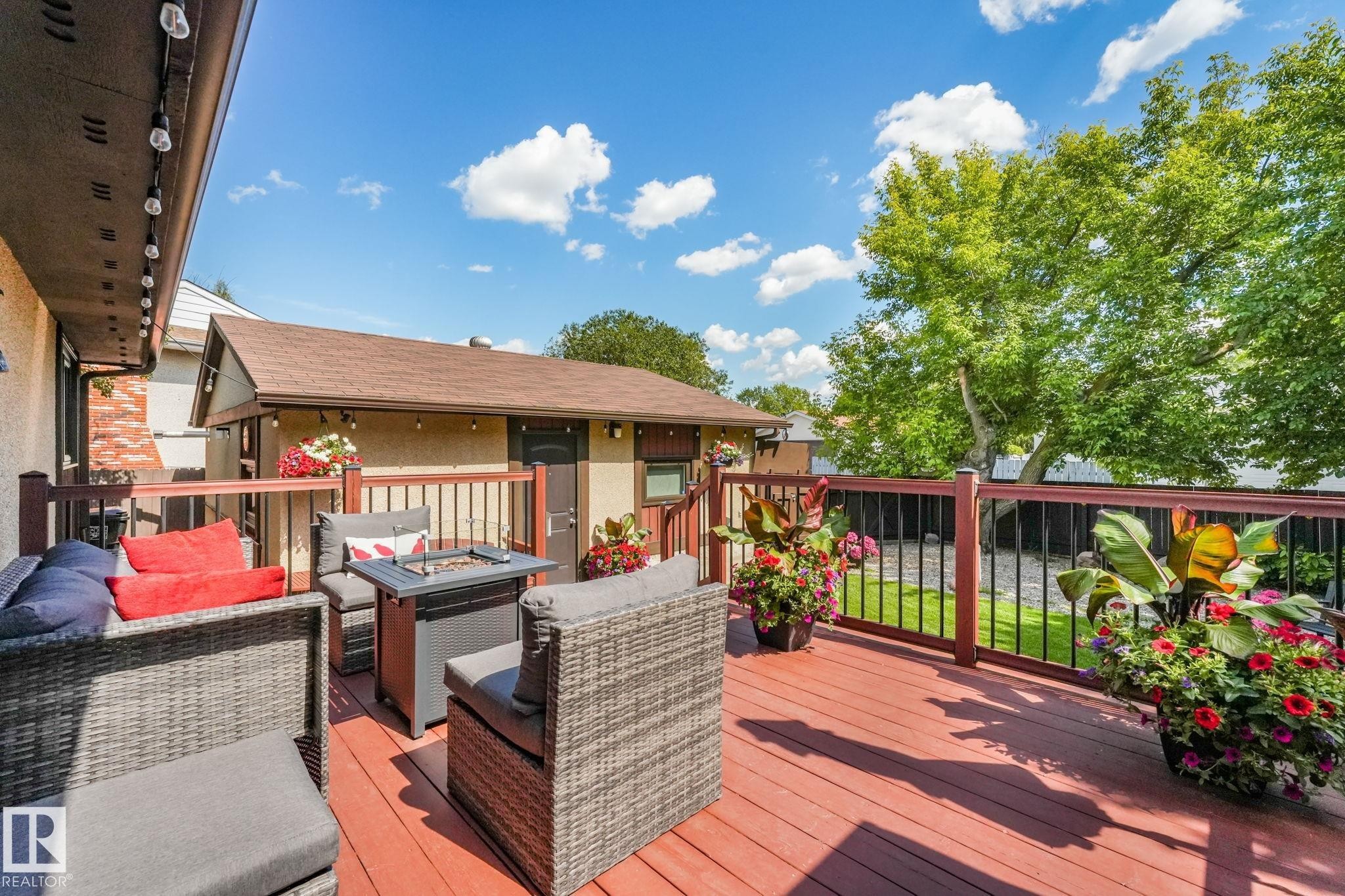 Expansive outdoor deck featuring red wood-finish flooring and dark wood-tone railings with black balusters - 17237 104 Street, Edmonton, AB