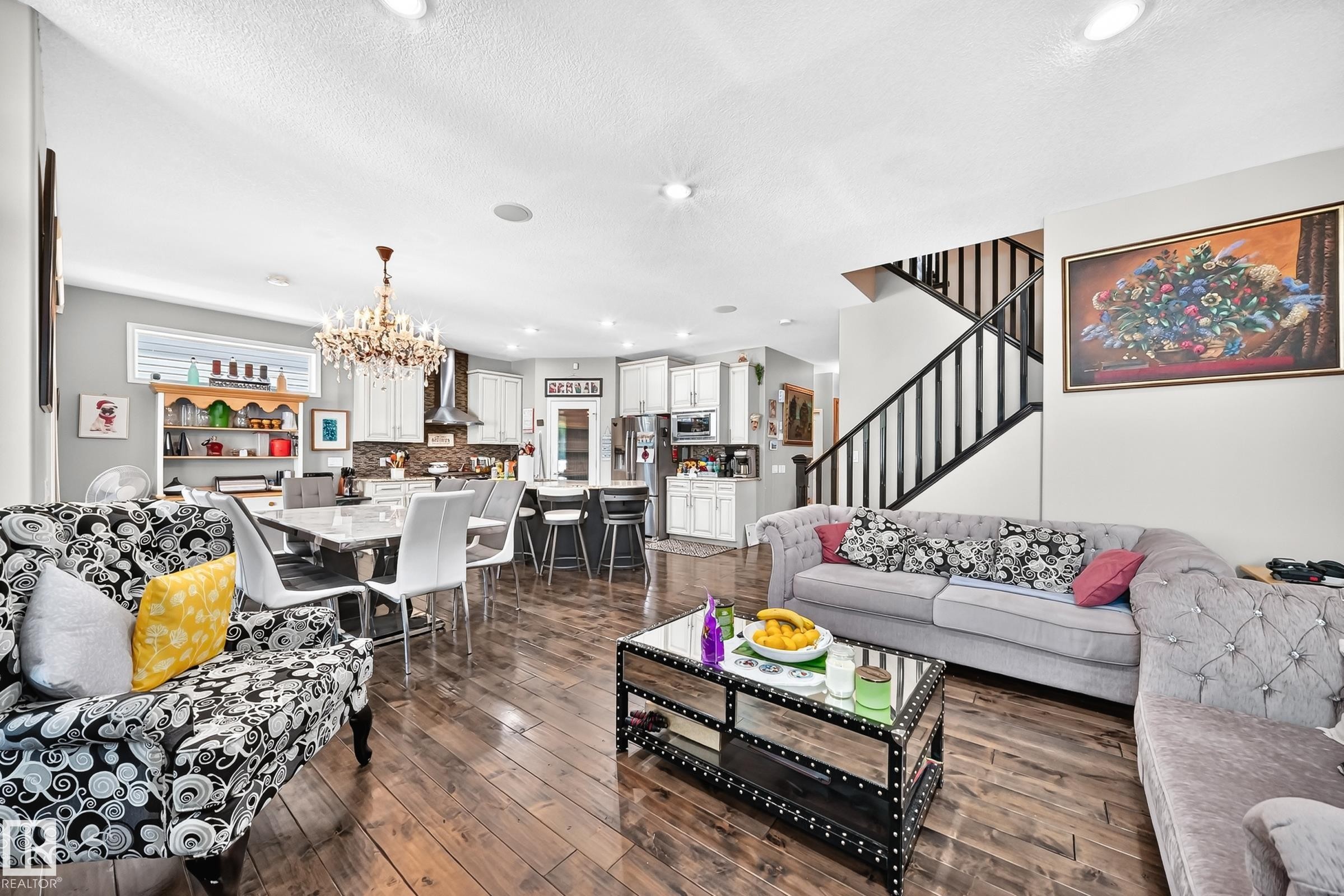 Open-concept living space featuring wood-finish flooring, recessed lighting, and a prominent staircase with dark railings - 12410 171A Avenue, Edmonton, AB