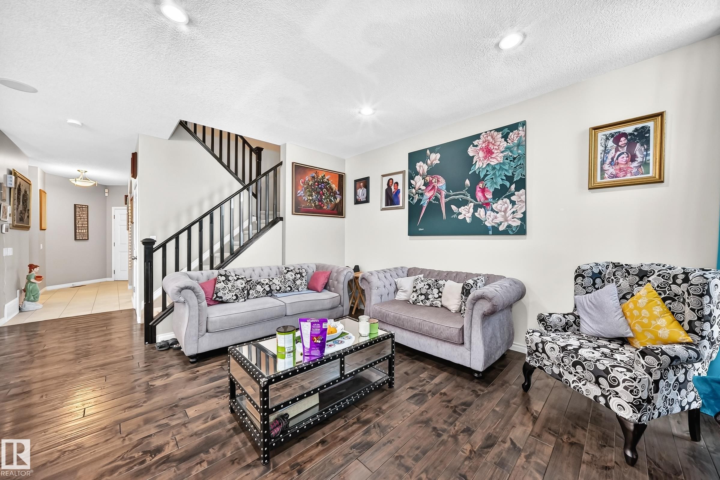 Living area featuring wood-finish flooring, recessed lighting, and a staircase with black railings - 12410 171A Avenue, Edmonton, AB