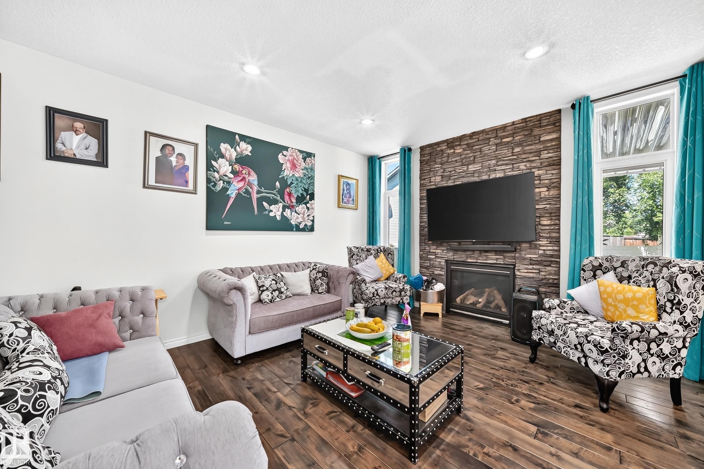 Spacious living area featuring wood-finish flooring, recessed lighting, and a stone accent wall - 12410 171A Avenue, Edmonton, AB