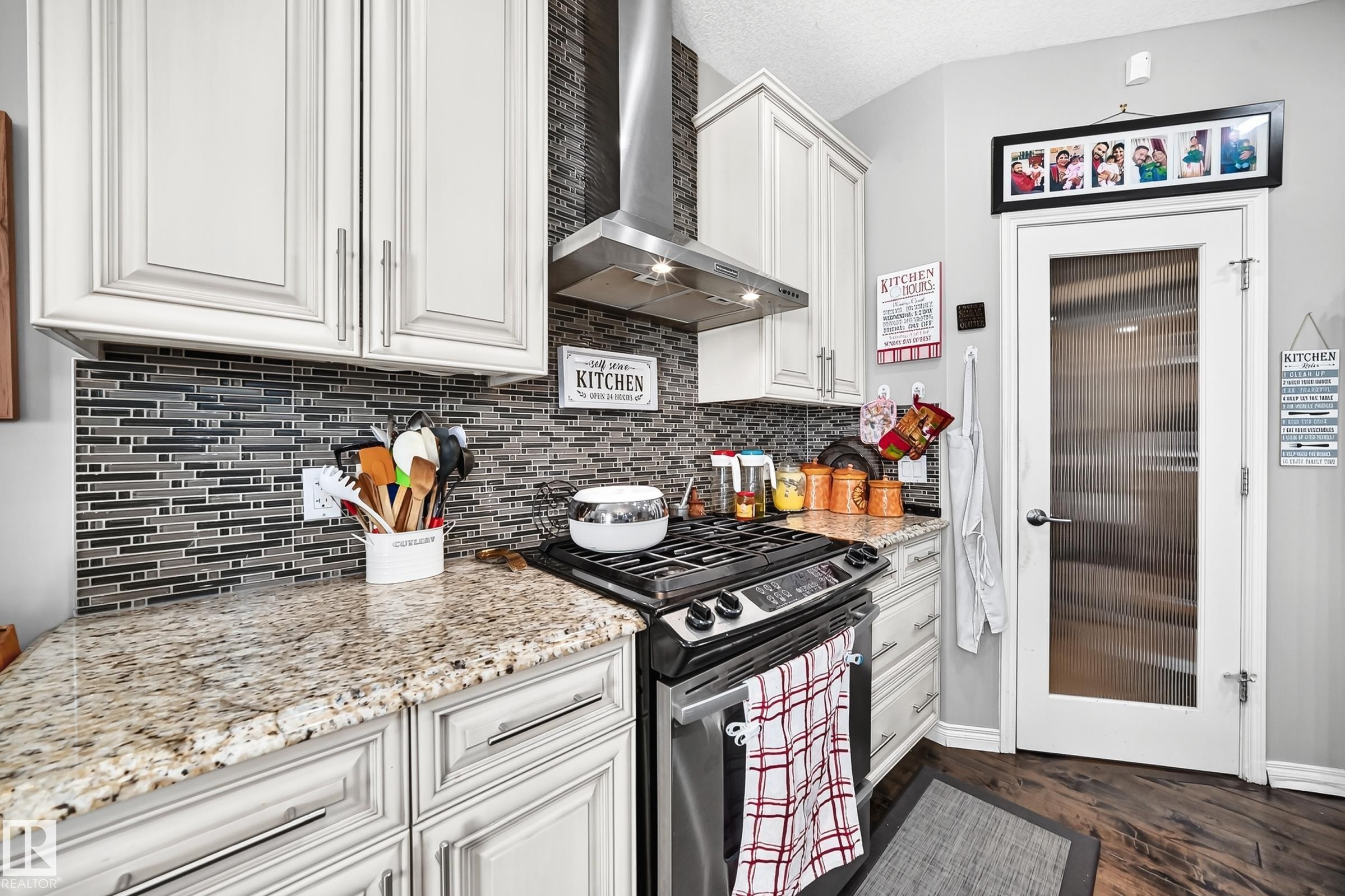 Kitchen featuring light-toned cabinetry, a mosaic tile backsplash, and granite-style countertops - 12410 171A Avenue, Edmonton, AB