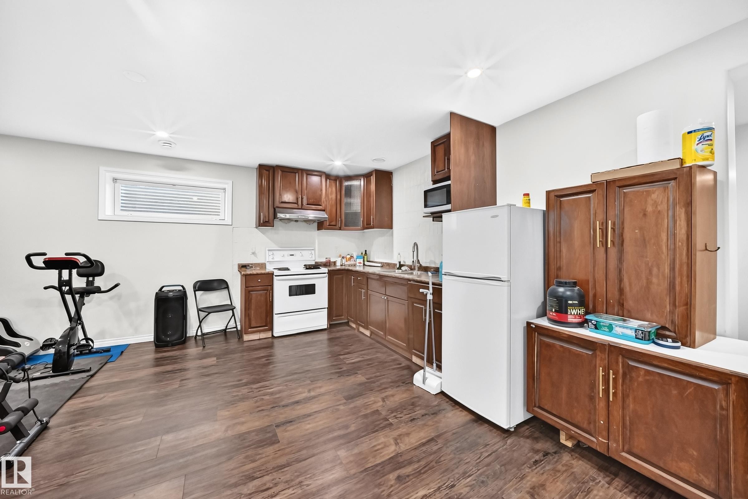 Kitchen area featuring wood-finish flooring, wood cabinetry, a white range, and a stainless steel sink with a gooseneck faucet - 12410 171A Avenue, Edmonton, AB