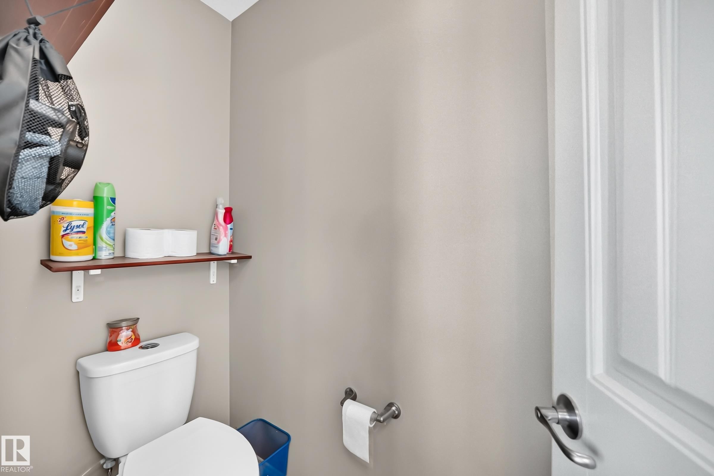 White toilet with a built-in toilet paper dispenser and a wood-finish shelf - 12410 171A Avenue, Edmonton, AB