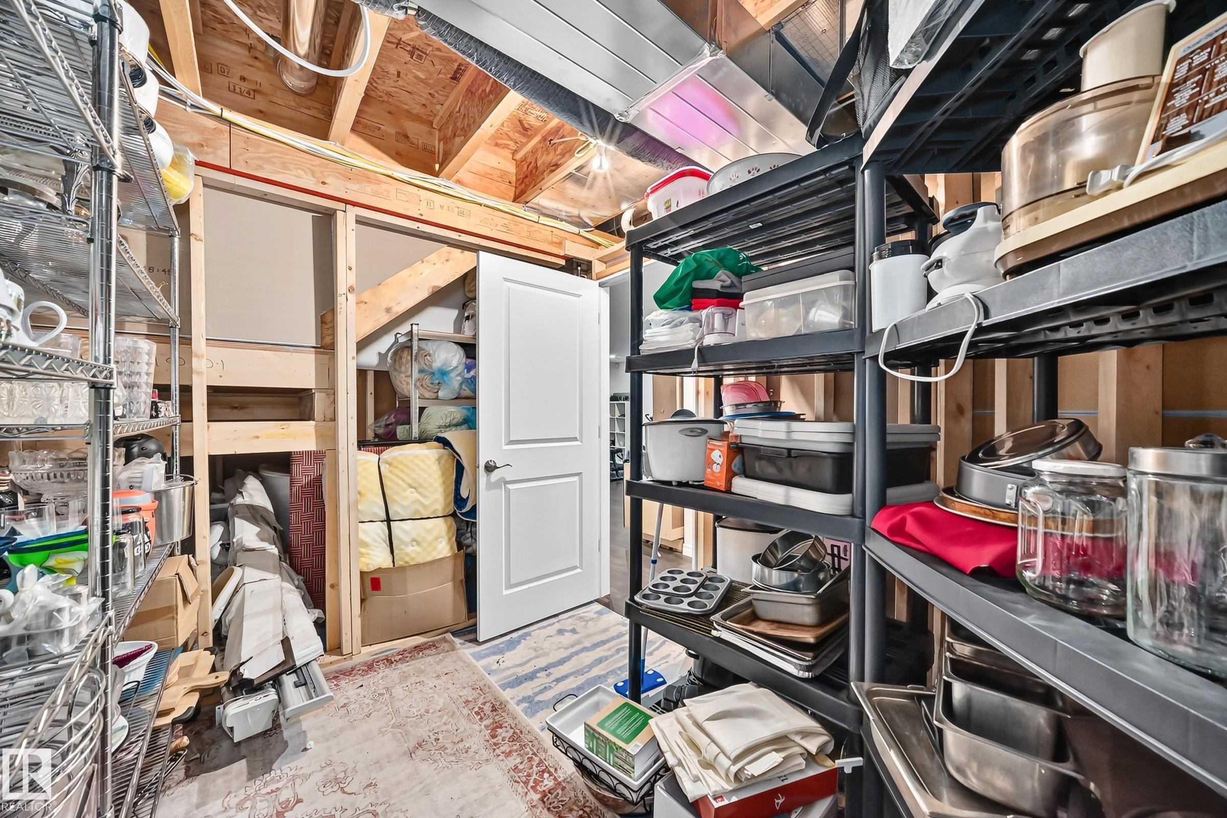 Utility space featuring exposed wood framing, metal shelving, and a paneled white door - 12410 171A Avenue, Edmonton, AB
