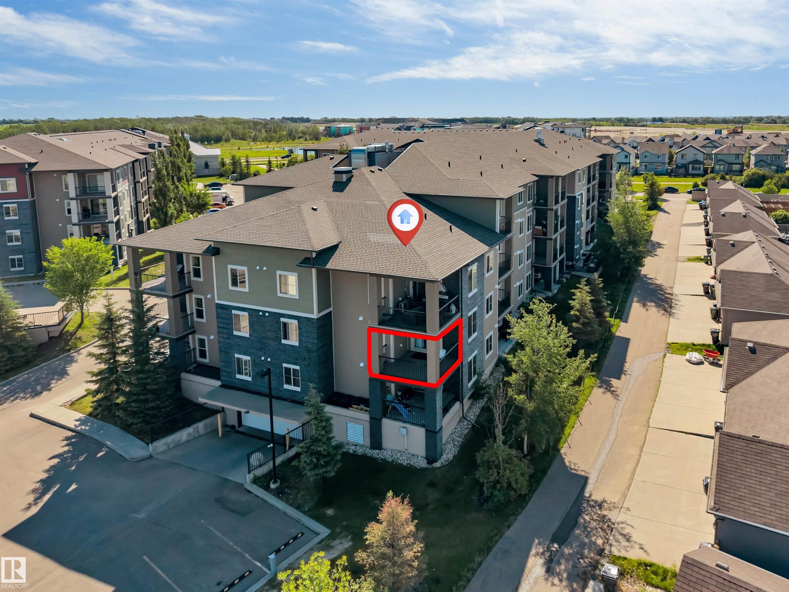Contemporary multi-story condominium building featuring a stone and siding exterior, private balconies, and an attached parking area - 225 111 Watt Common, Edmonton, AB