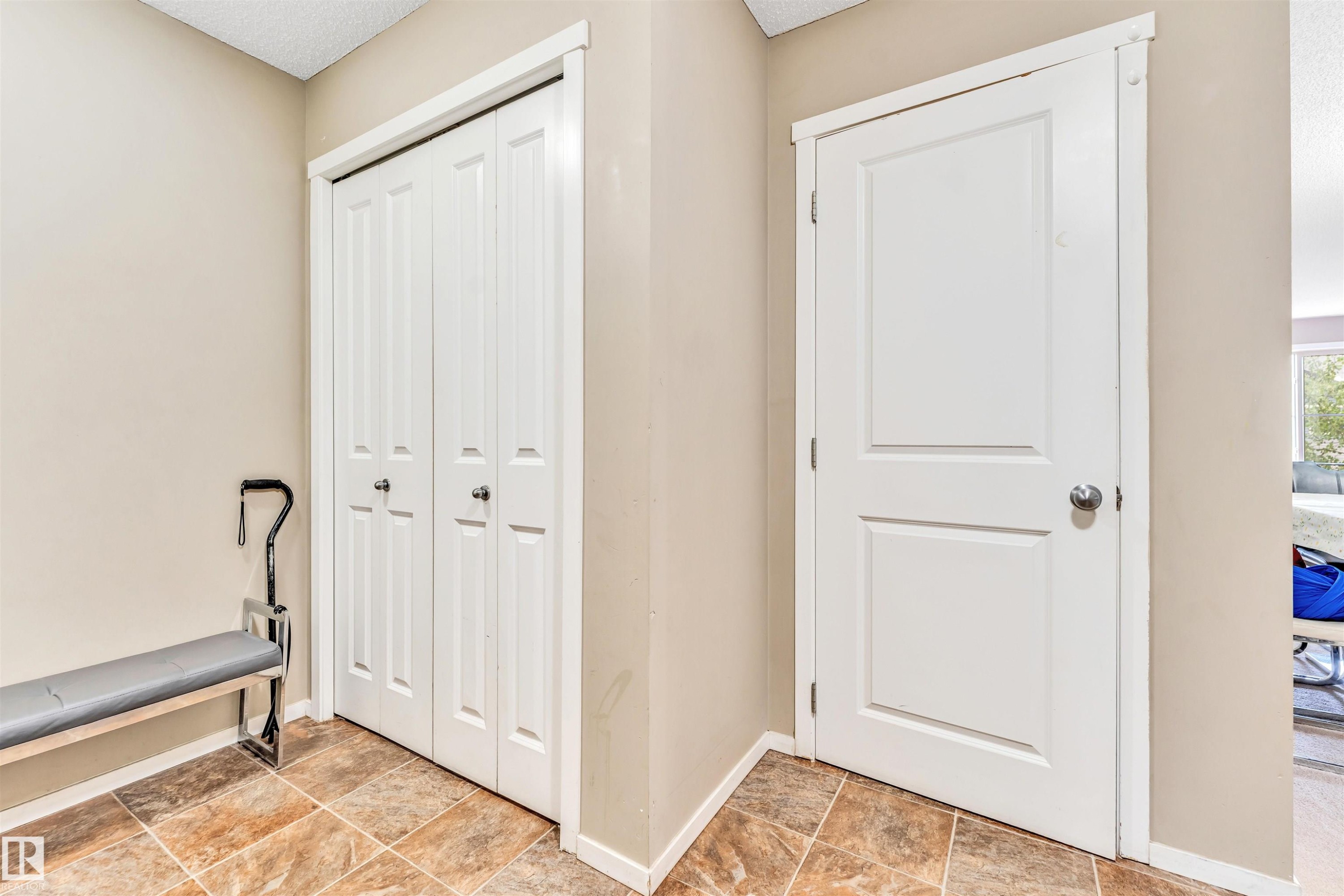 Tiled flooring entry area featuring a two-panel interior door with a chrome knob, and bi-fold closet doors with matching hardware - 225 111 Watt Common, Edmonton, AB