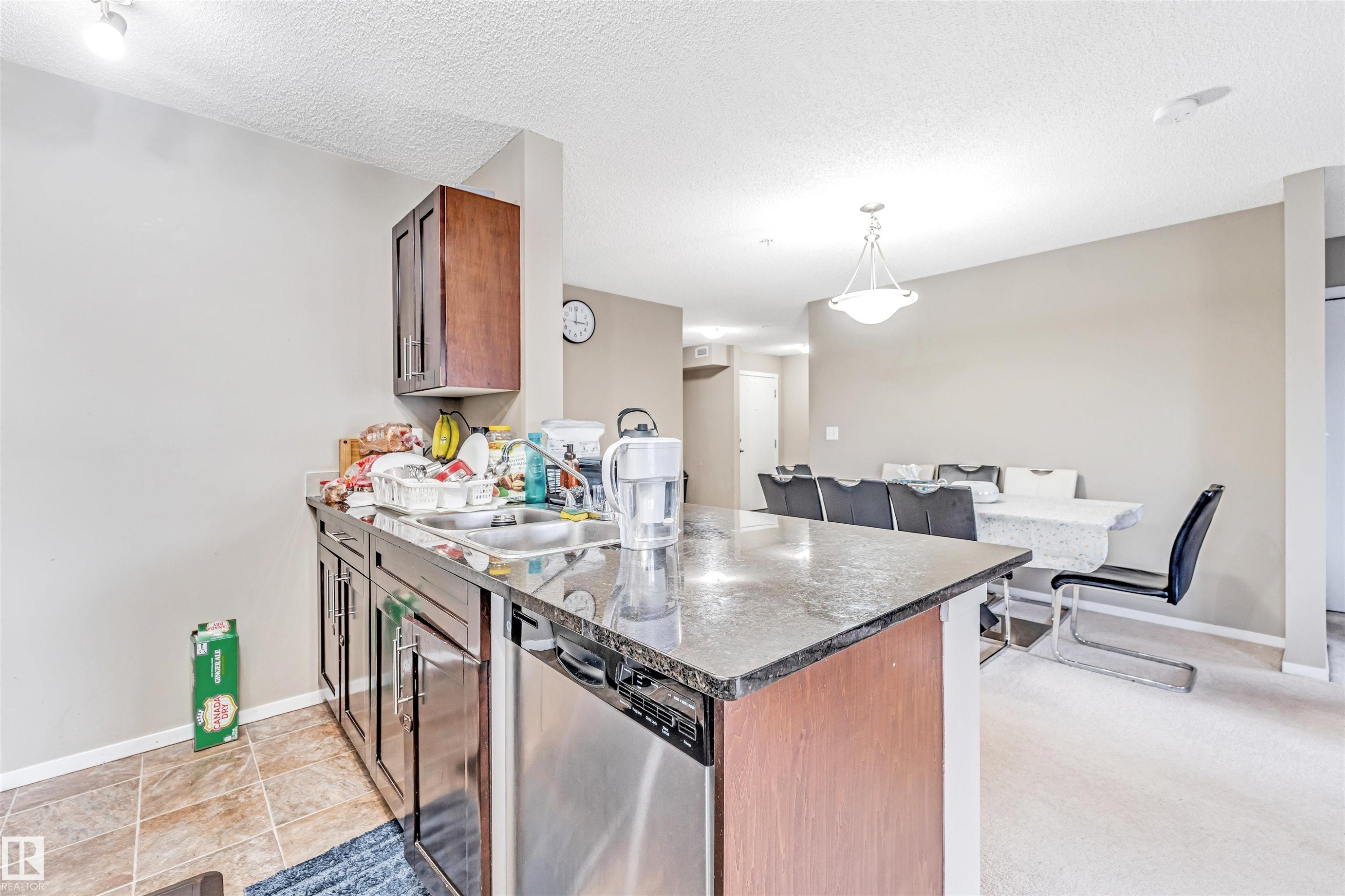 Kitchen island with granite-style countertop and integrated stainless steel dishwasher - 225 111 Watt Common, Edmonton, AB
