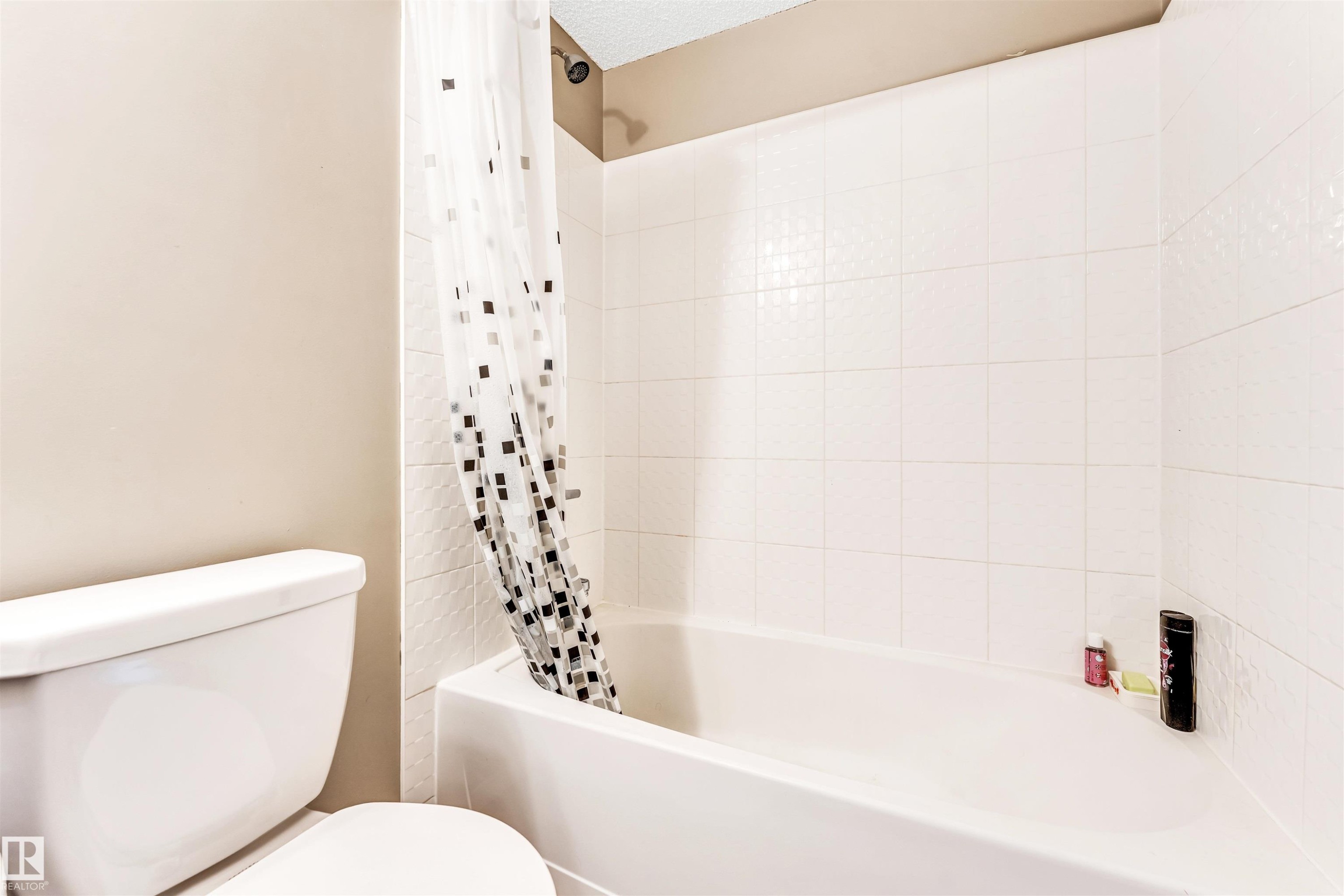 White tiled shower surround with a built-in tub and showerhead - 225 111 Watt Common, Edmonton, AB