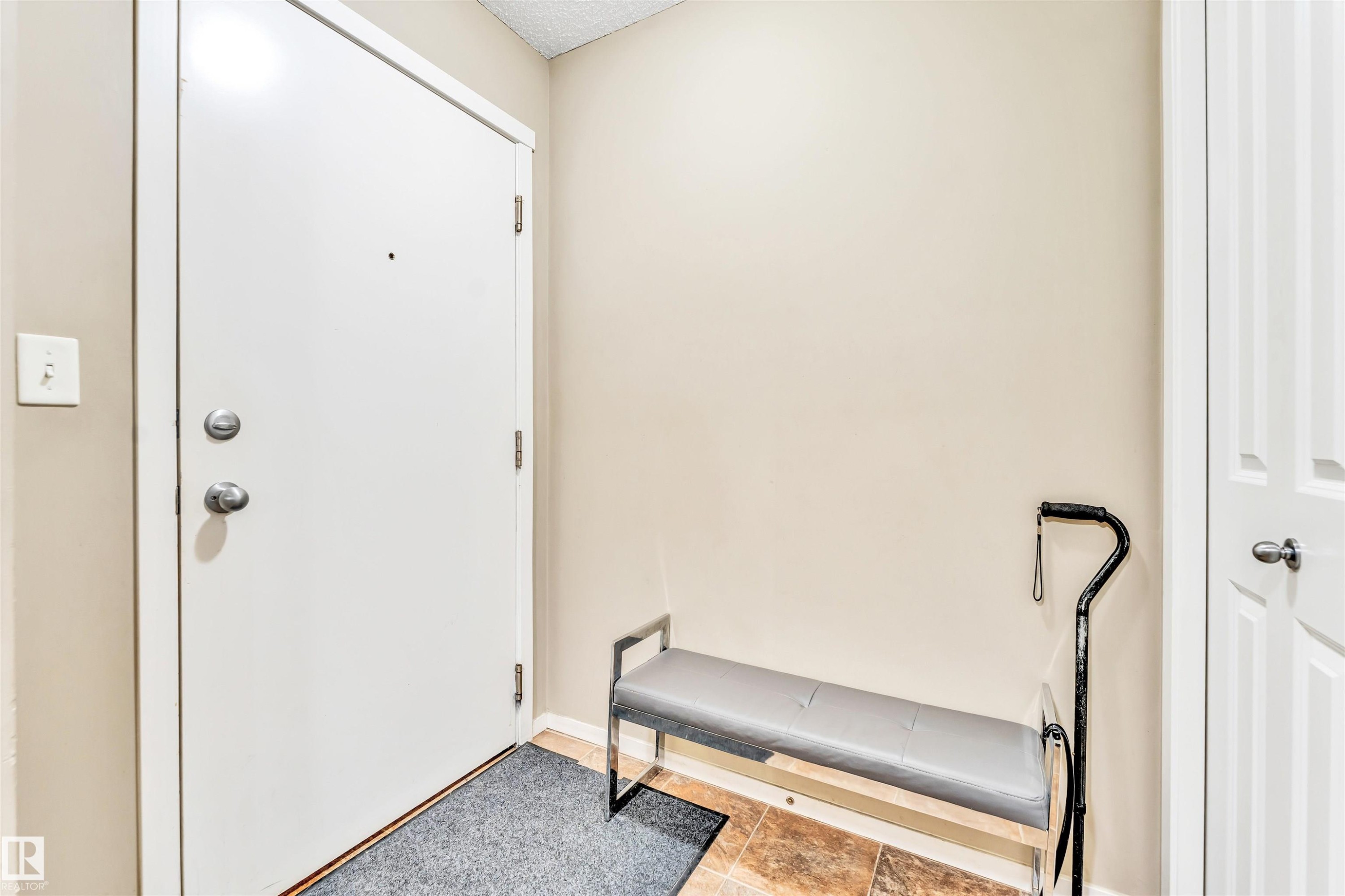 Entryway featuring a white door with brushed nickel hardware, neutral wall paint, and a textured ceiling - 225 111 Watt Common, Edmonton, AB