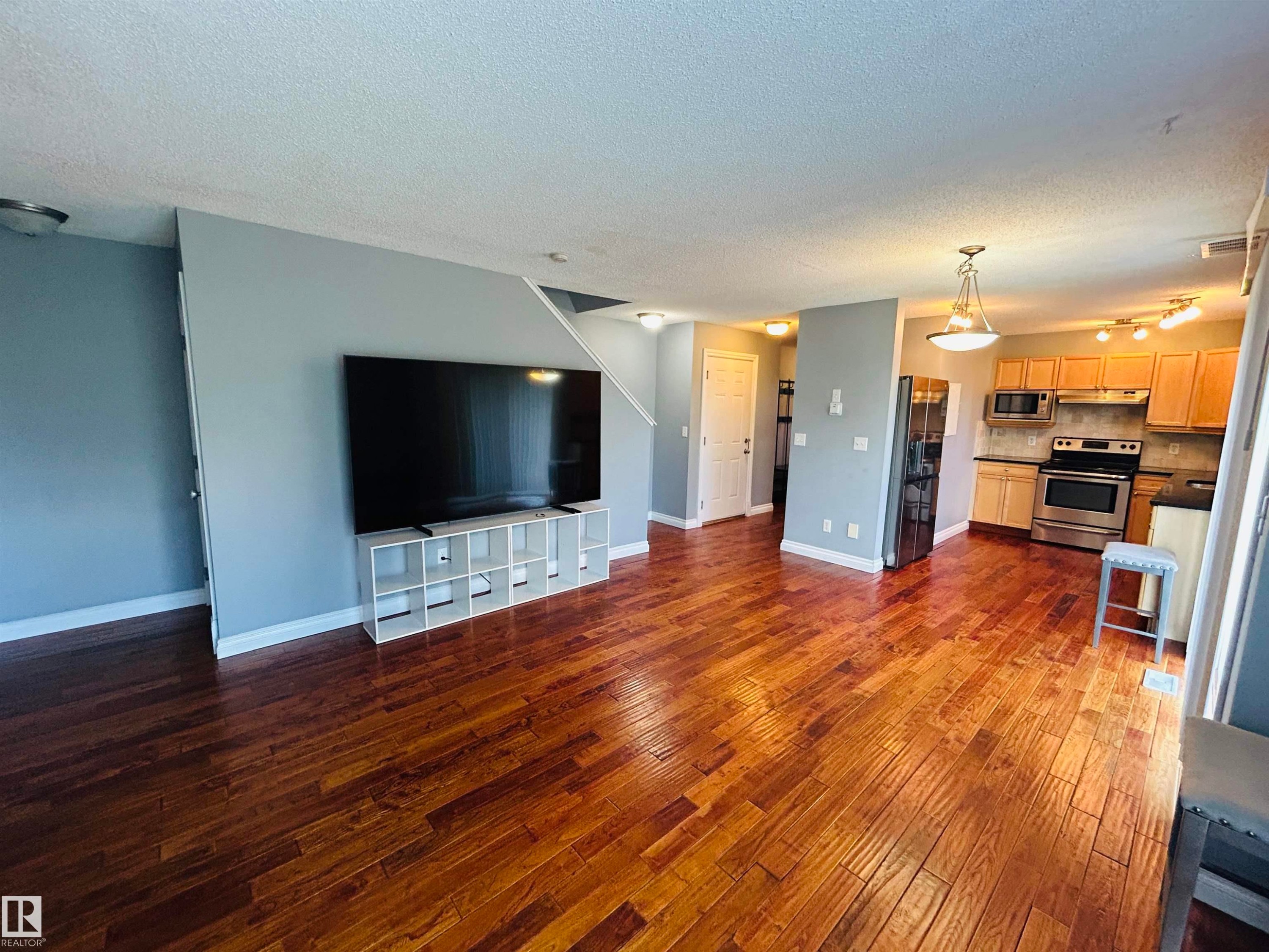 Open-concept living area featuring rich wood-finish flooring - 89 12050 17 Avenue, Edmonton, AB