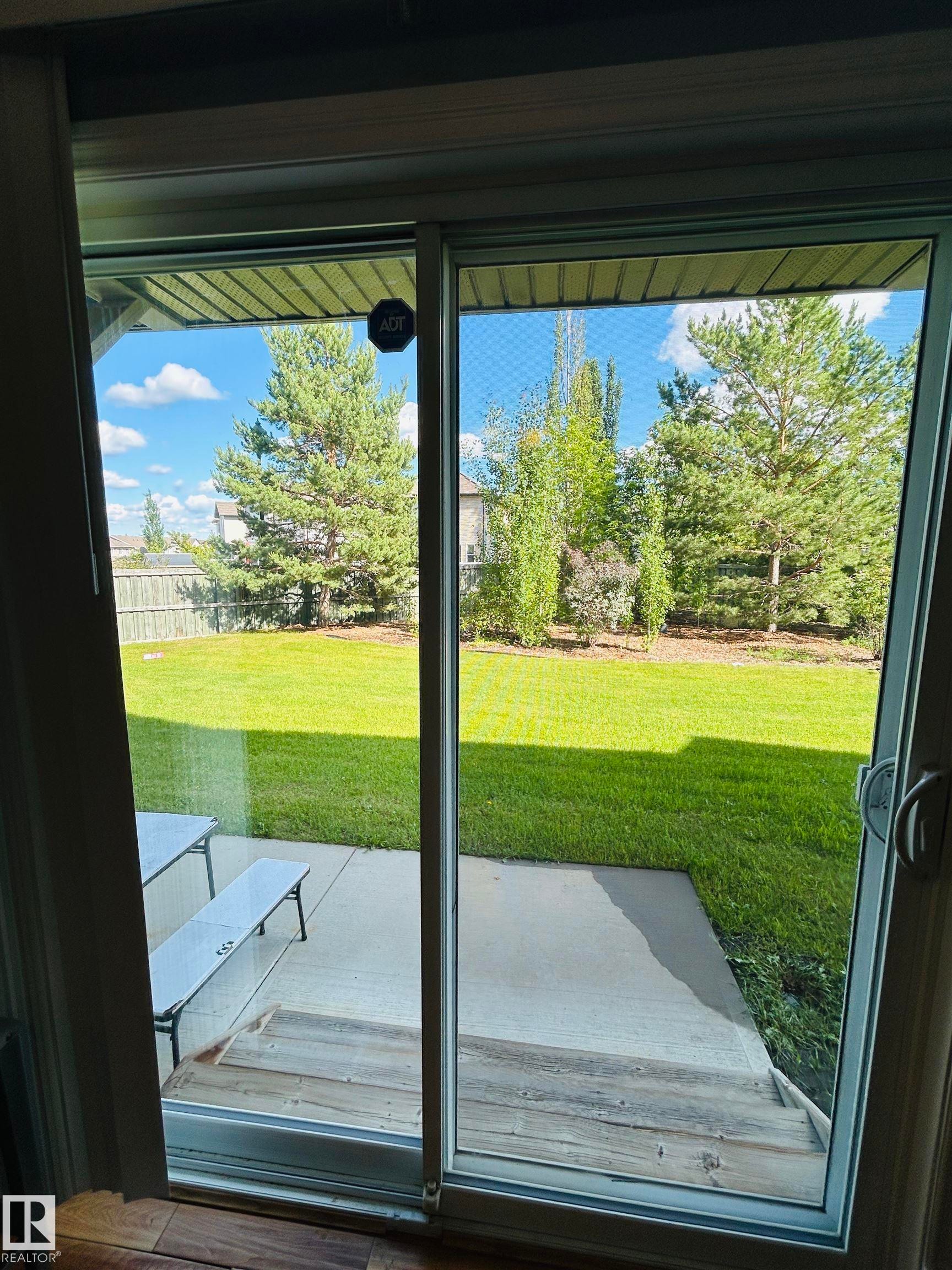 Sliding glass door opening onto a concrete patio with wood-finish steps - 89 12050 17 Avenue, Edmonton, AB