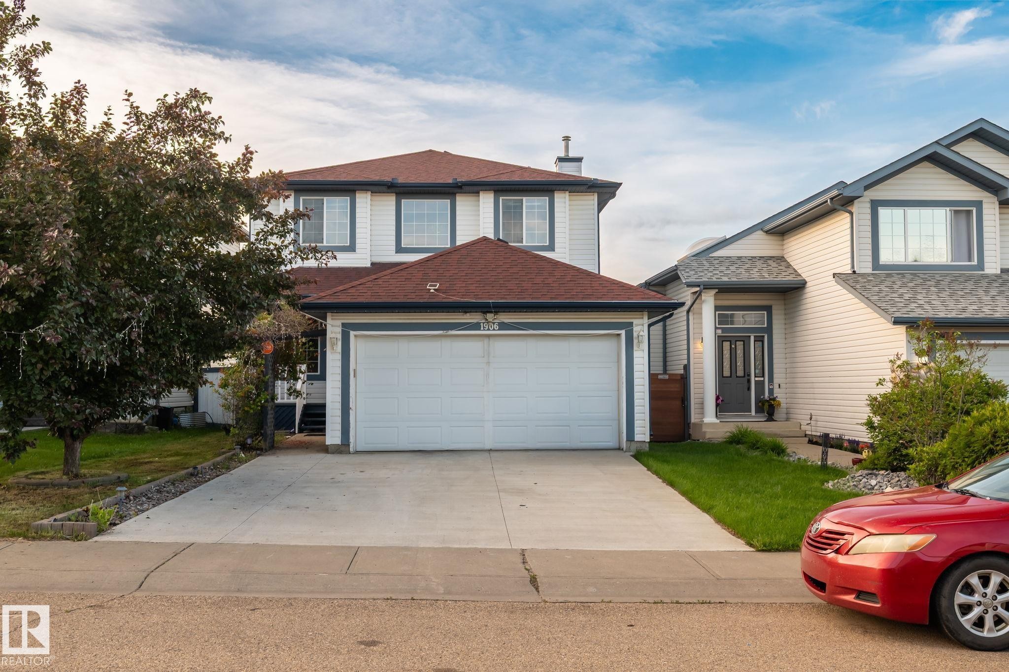 Two-story residence featuring light-colored siding with dark trim accents and a red shingle roof - 1906 37B Av Nw, Edmonton, AB - Outdoor With Facade