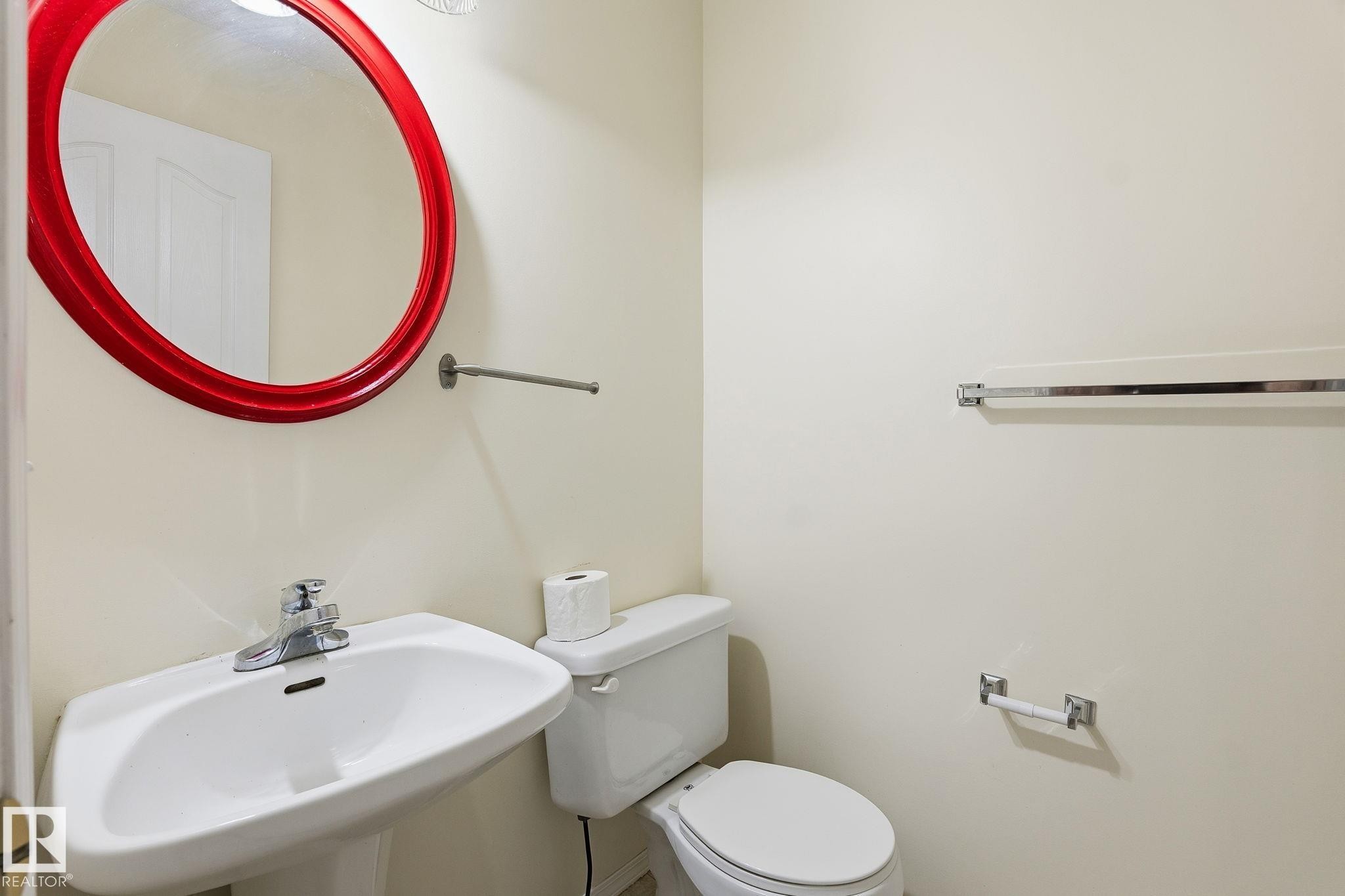Pedestal sink with chrome faucet and red oval mirror - 1906 37B Av Nw, Edmonton, AB - Indoor Photo Showing Bathroom