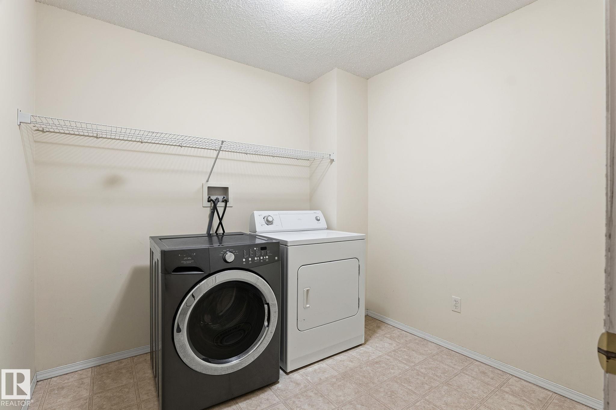 Dedicated laundry area featuring tile flooring, a wire shelving unit, and neutral wall paint - 1906 37B Av Nw, Edmonton, AB - Indoor Photo Showing Laundry Room