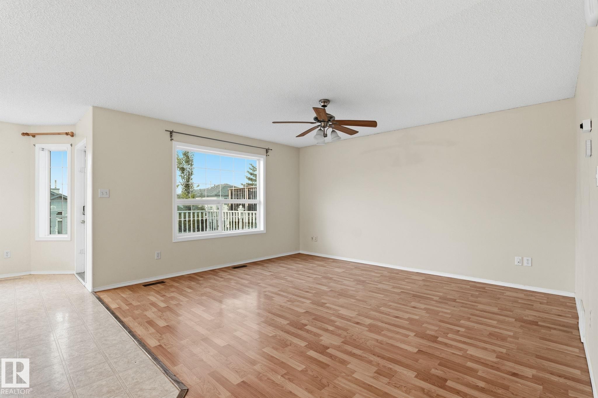 Spacious room with wood-finish flooring, a contemporary ceiling fan, and large windows providing abundant natural light - 1906 37B Av Nw, Edmonton, AB - Indoor Photo Showing Other Room