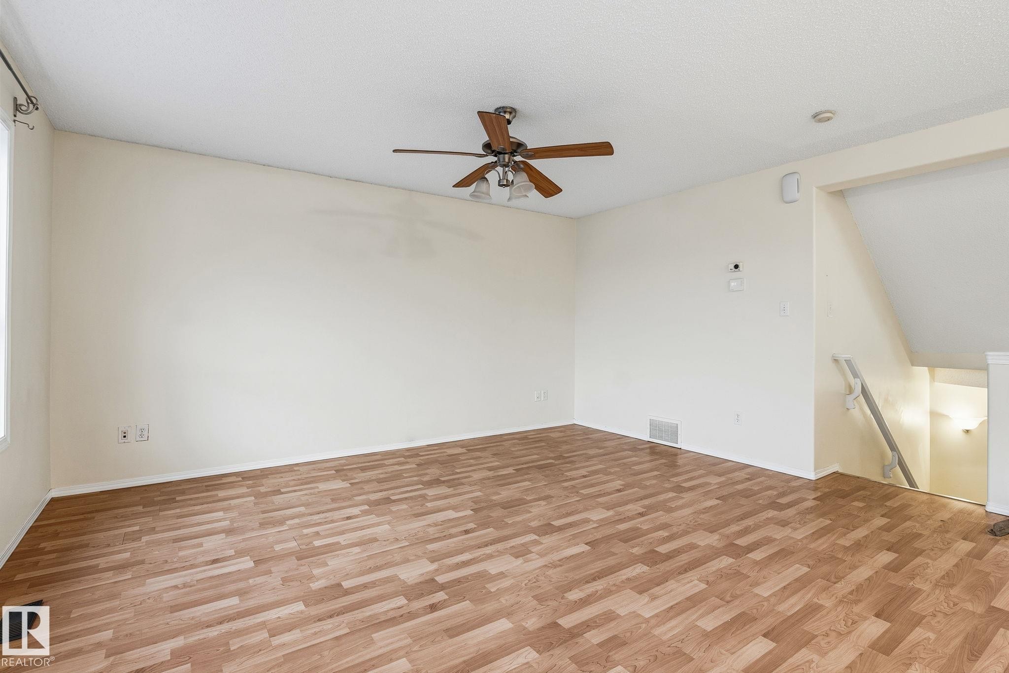 Spacious room featuring wood-finish flooring, light-colored walls, and a ceiling fan with integrated lighting - 1906 37B Av Nw, Edmonton, AB - Indoor Photo Showing Other Room