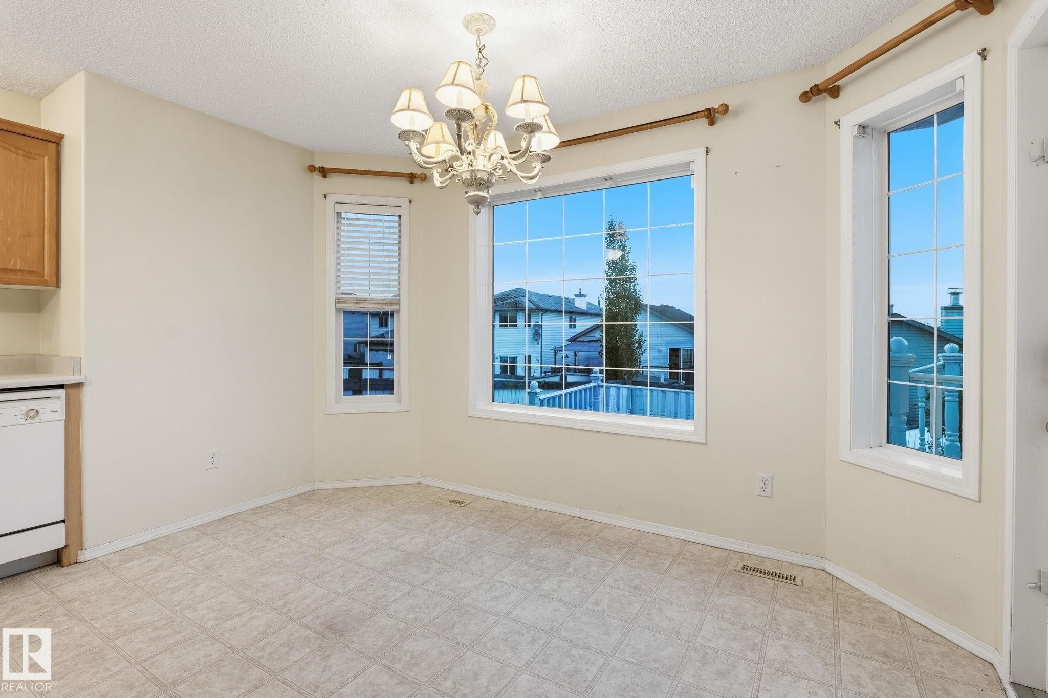 Bright dining area featuring a prominent bay window with white frames and grid patterns - 1906 37B Av Nw, Edmonton, AB - Indoor Photo Showing Other Room