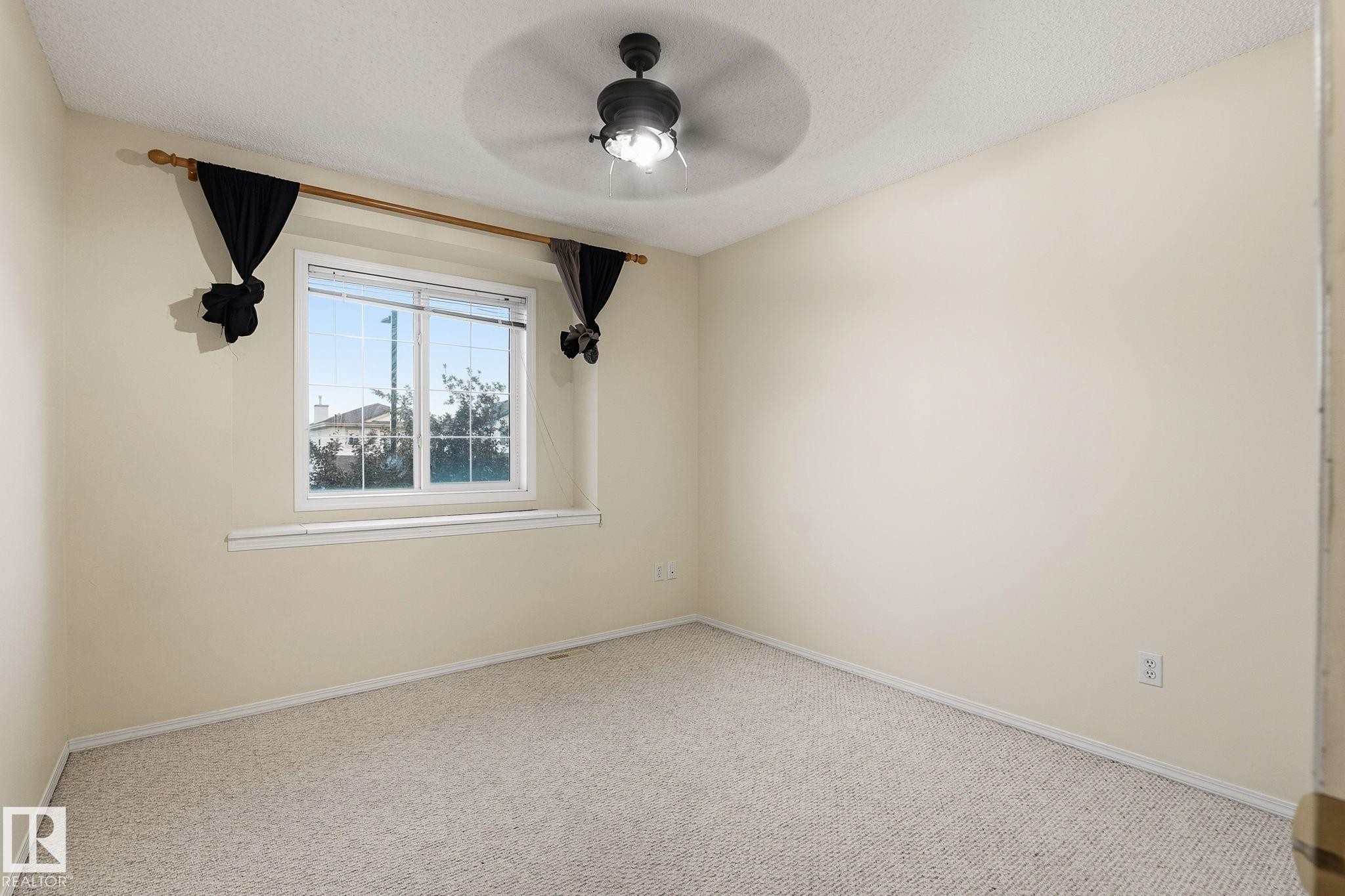 Carpeted room featuring neutral wall tones, a ceiling fan with integrated lighting, and a window with a white frame - 1906 37B Av Nw, Edmonton, AB - Indoor Photo Showing Other Room