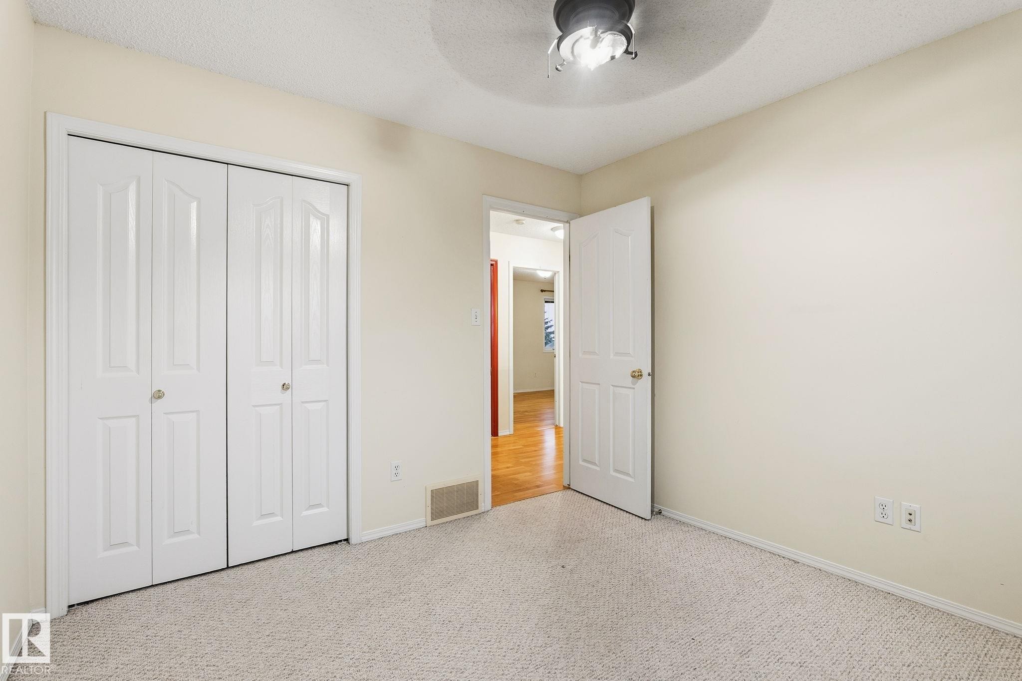 Neutral-toned carpeting paired with light-colored walls and a ceiling-mounted fan - 1906 37B Av Nw, Edmonton, AB - Indoor