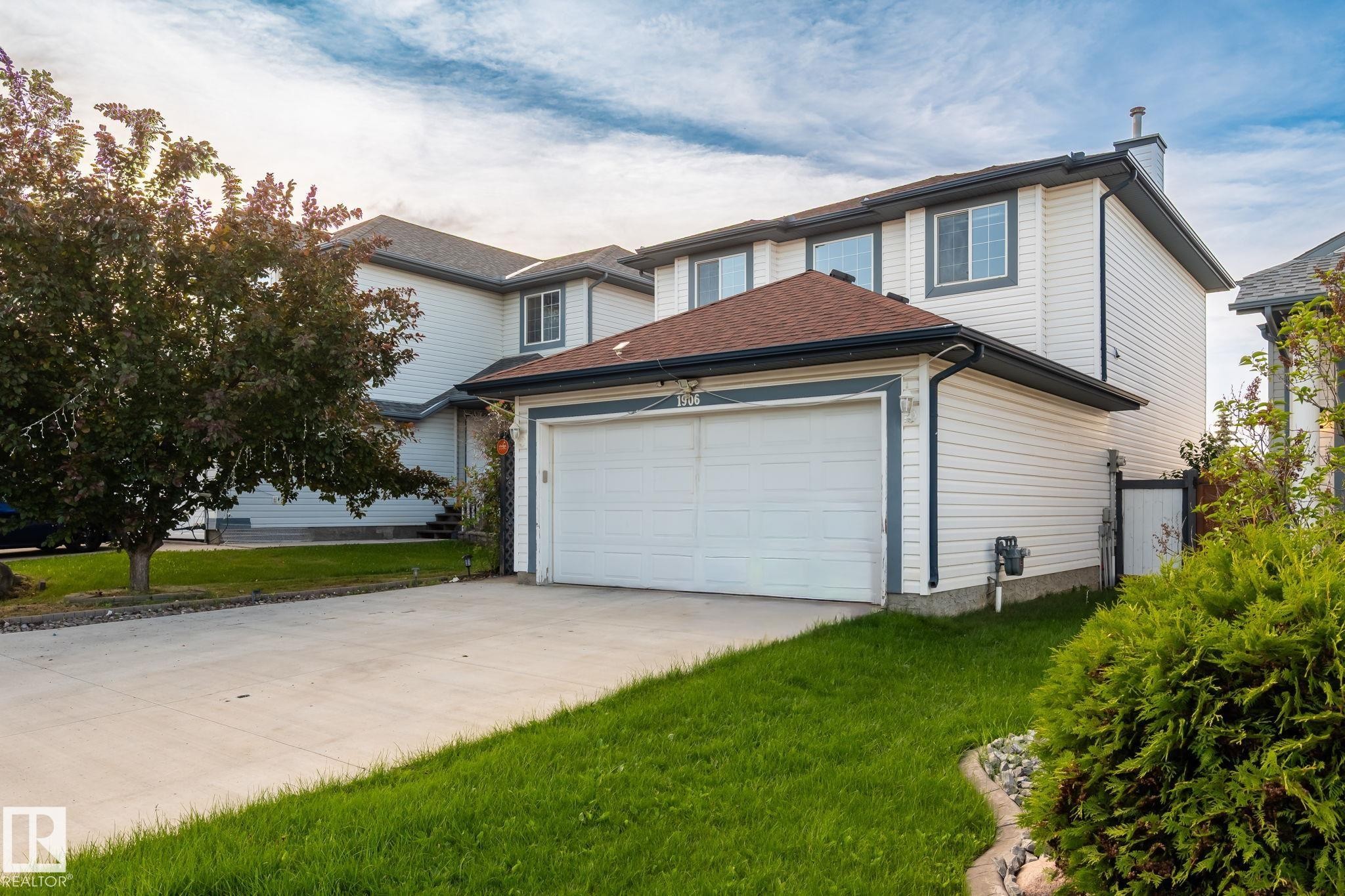 Two-story residence featuring white siding, a two-car garage, and a concrete driveway - 1906 37B Av Nw, Edmonton, AB - Outdoor