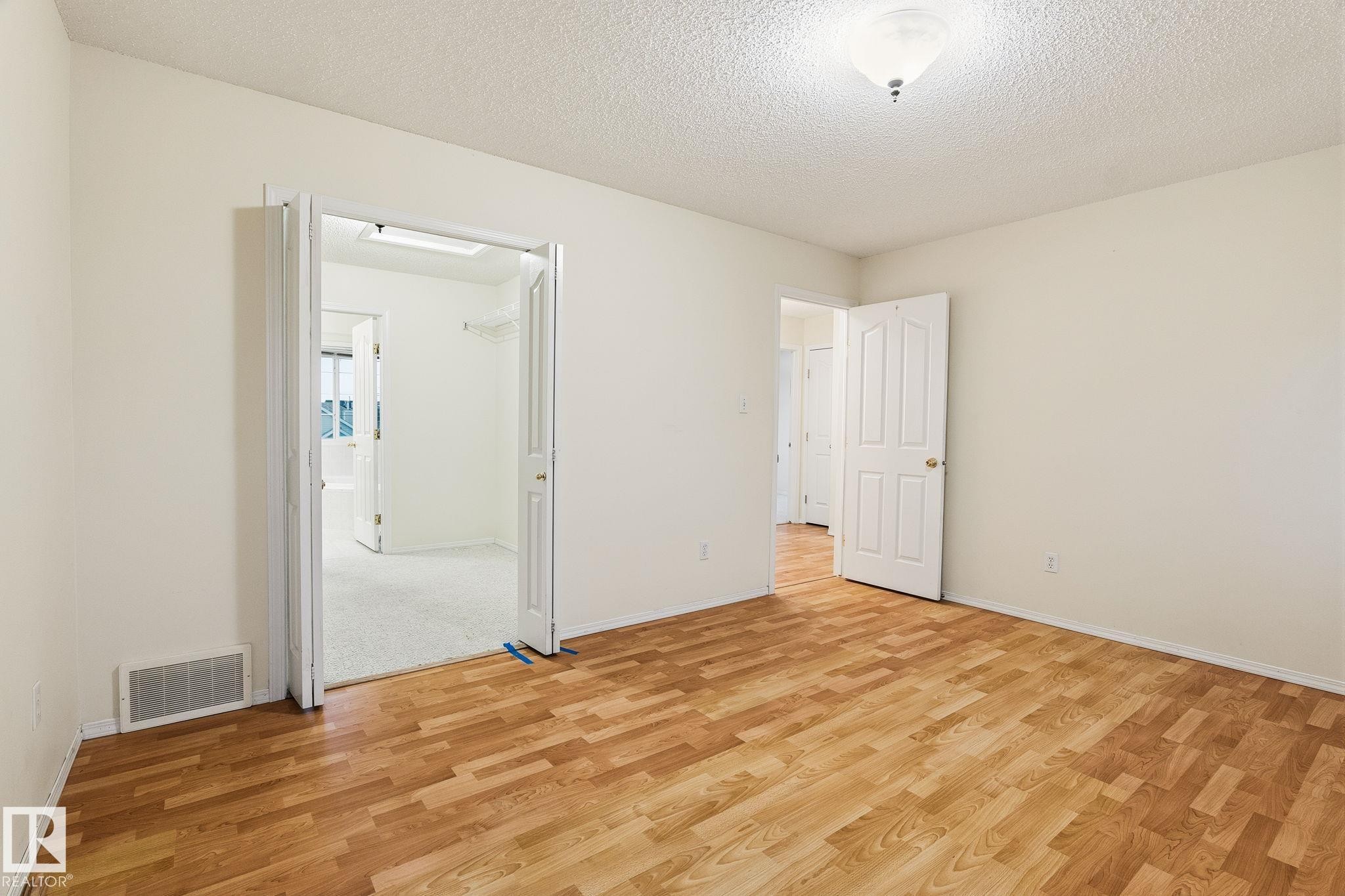 Interior room featuring wood-finish flooring, white walls, and a white ceiling with a flush-mount light fixture - 1906 37B Av Nw, Edmonton, AB - Indoor Photo Showing Other Room