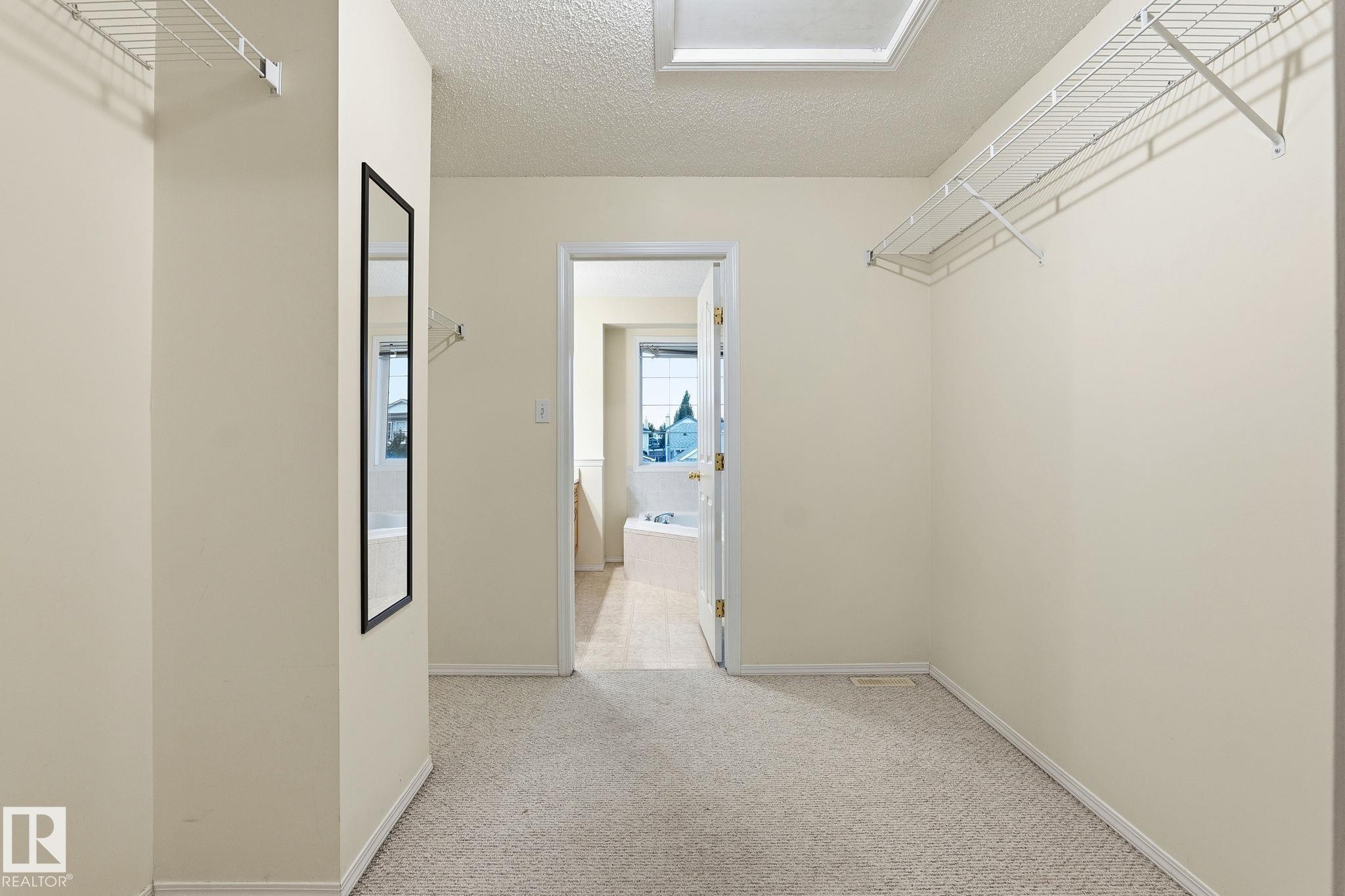 Carpeted walk-in closet with overhead wire shelving and a full-length mirror - 1906 37B Av Nw, Edmonton, AB - Indoor