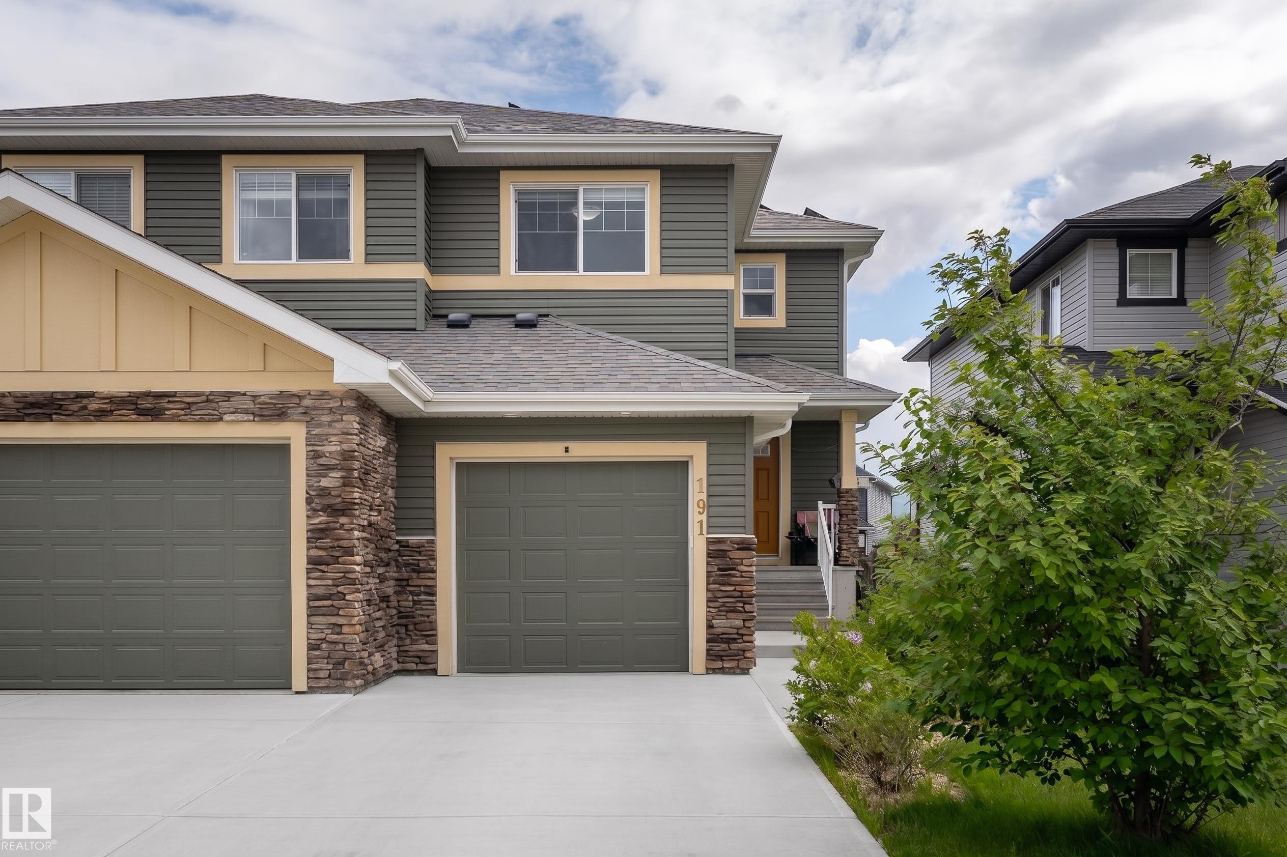 Contemporary exterior featuring multi-toned siding, stacked stone accents, and a dual garage - 191 Reed Place, Leduc, AB - Outdoor With Facade