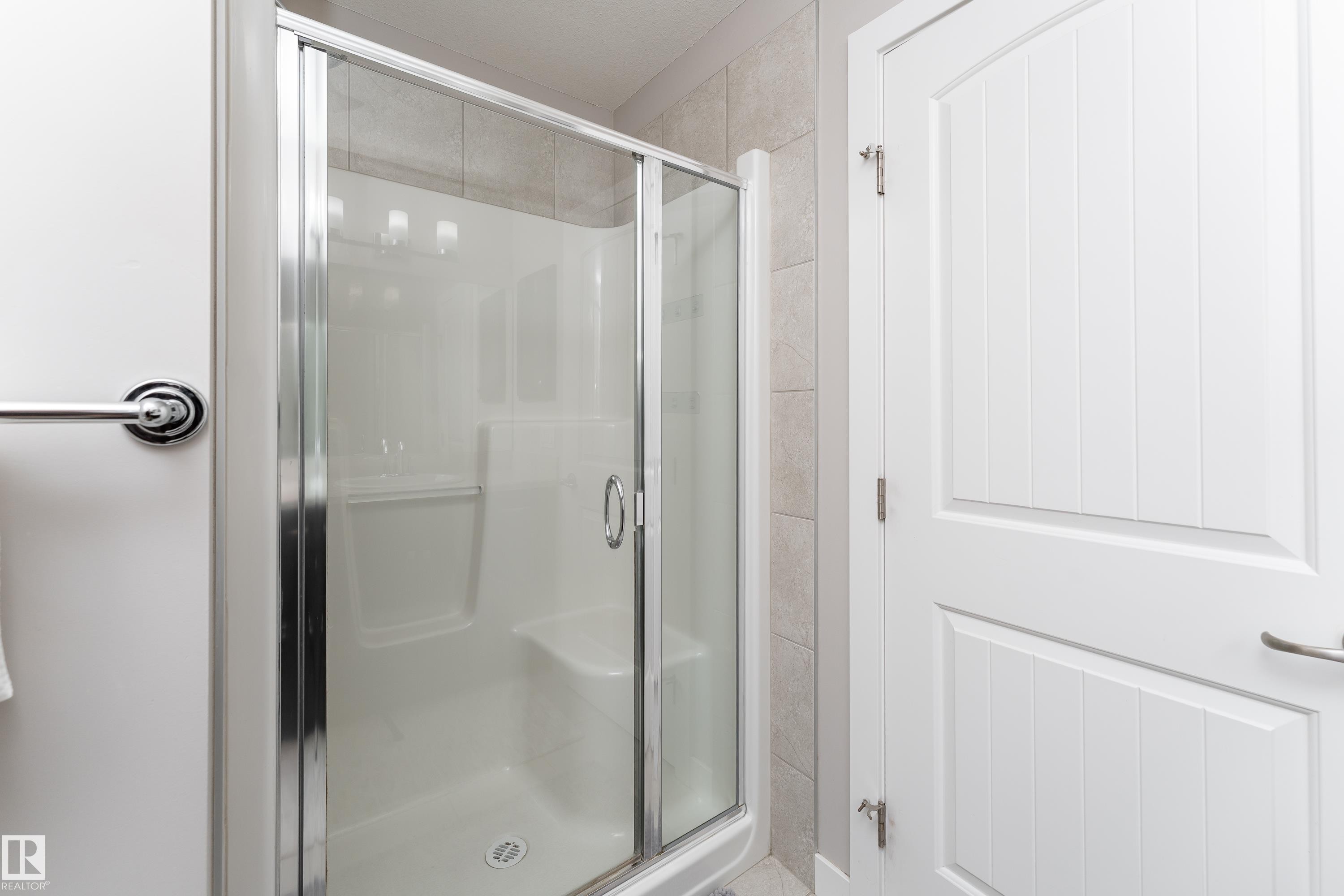 Shower enclosure with clear glass sliding doors and a white composite base - 191 Reed Place, Leduc, AB - Indoor Photo Showing Bathroom